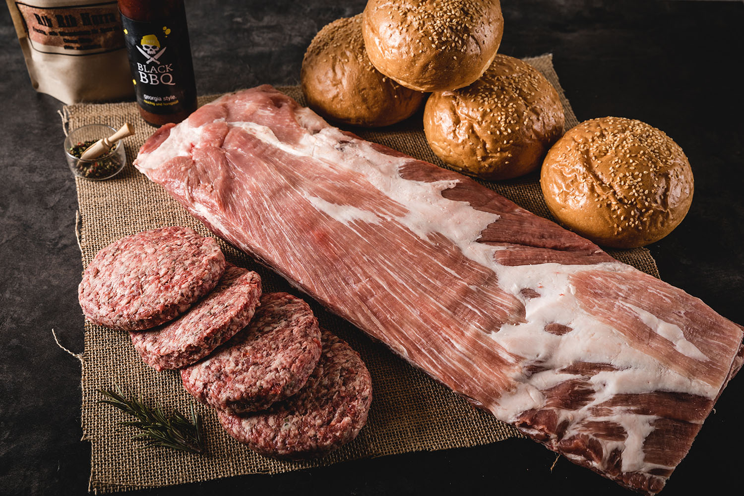 Burger-Paket mit saftigen Beef Ribs, Rindfleisch-Patties, Burgerbrötchen, BBQ-Saucen und Gewürzen, ansprechend auf Holztisch angerichtet – hochwertiges Fleisch aus der Oberpfalz für Burger-Liebhaber.