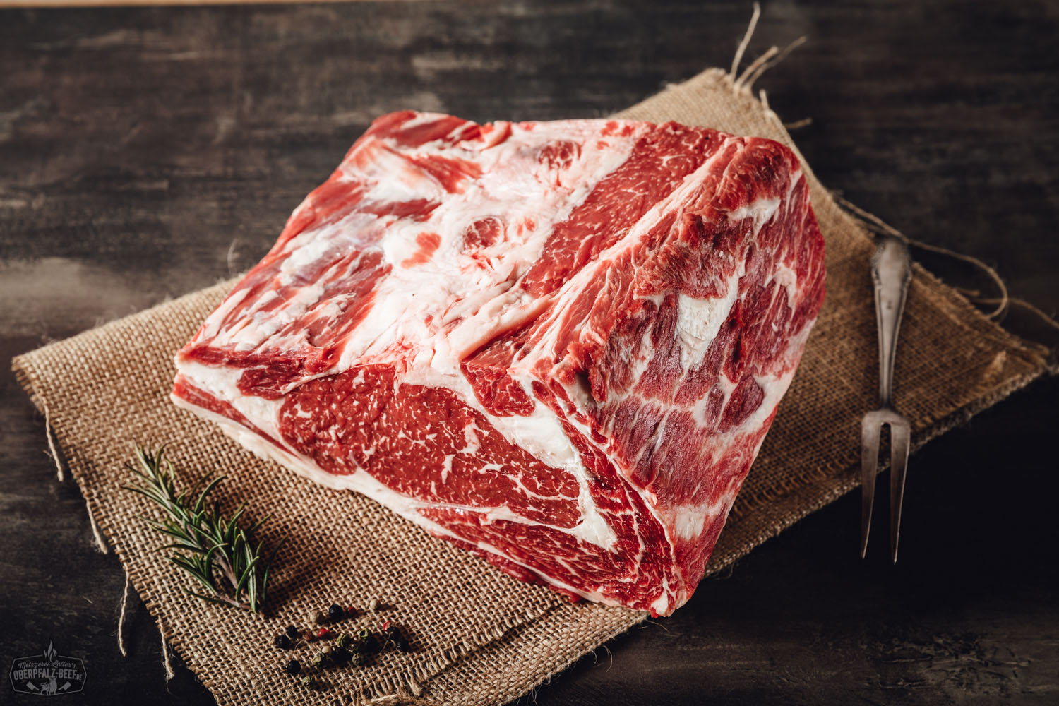 Entrecôte am Stück – Wet Aged Rib-Eye vom Oberpfalz-Rind Roastbeef am Stück vom Oberpfalz-Rind, Wet Aged gereift, roh und quer aufgeschnitten, auf schwarzem Untergrund präsentiert – gut marmoriertes Rindfleisch in Premiumqualität für Steak, Braten oder Grillgerichte.