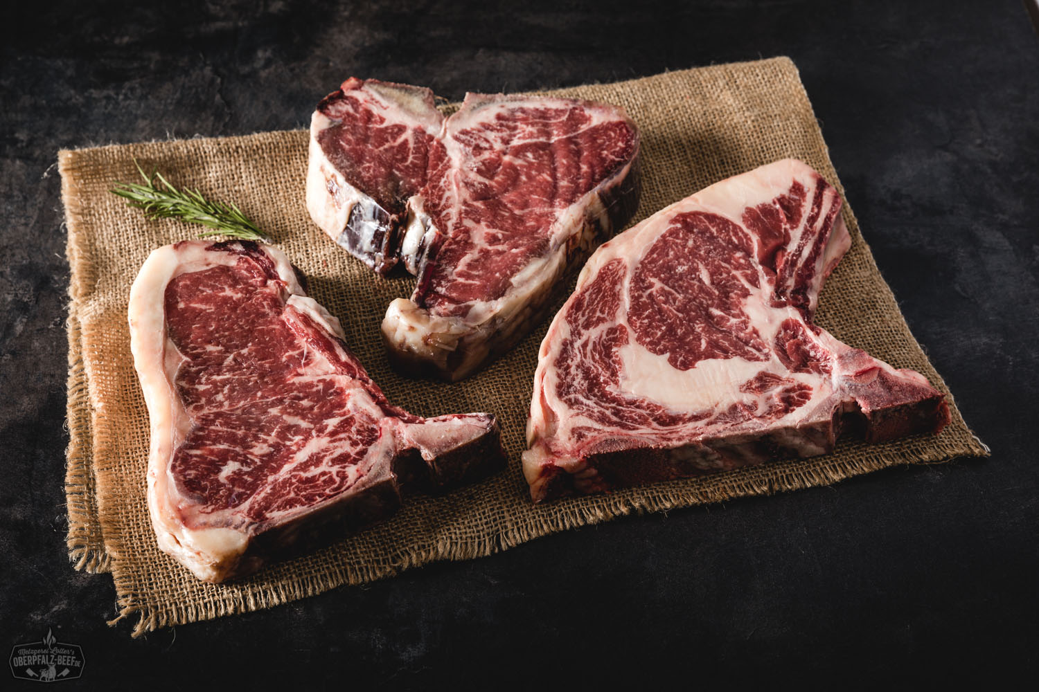 Dry Aged Bone-in-Steak aus Oberpfälzer Rindfleisch, roh und saftig marmoriert, auf dunklem Untergrund angerichtet – hochwertiges, handverlesenes Premium-Fleisch für Grill oder Pfanne.