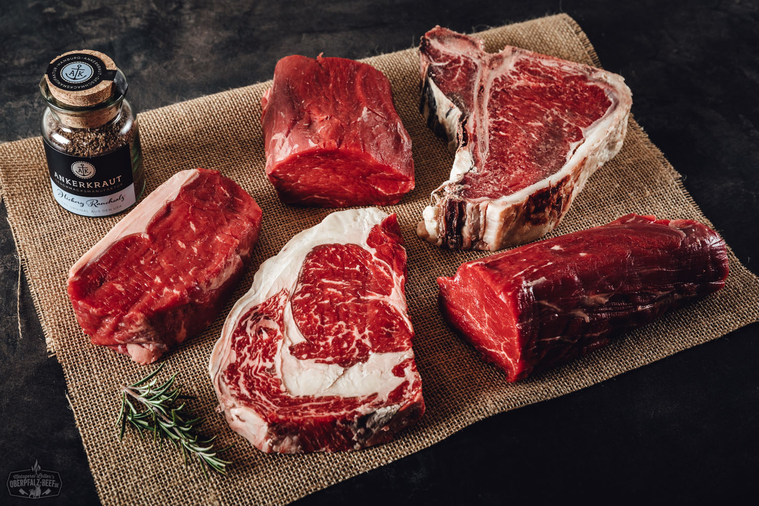 Drei saftige, medium-rare gegrillte Rindersteaks liegen auf einem Holzbrett, umgeben von frischem Rosmarin, grobem Meersalz und Pfefferkörnern; im Hintergrund liegt ein rustikales Messer – hochwertiges Rindfleisch, ideal für Grillfans und Steak-Liebhaber.