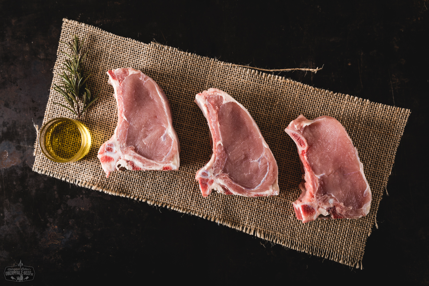 Kotelett vom Oberpfälzer Milchkalb auf Holzbrett – Regionales Kalbfleisch frisch zubereitet Frisch gebratenes Kotelett vom Oberpfälzer Milchkalb auf Holzbrett angerichtet, mit zarter, goldbrauner Kruste, saftigem rosa Fleischinneren und dekorativem Rosmarinzweig – hochwertiges Kalbfleischgericht in rustikaler Präsentation.