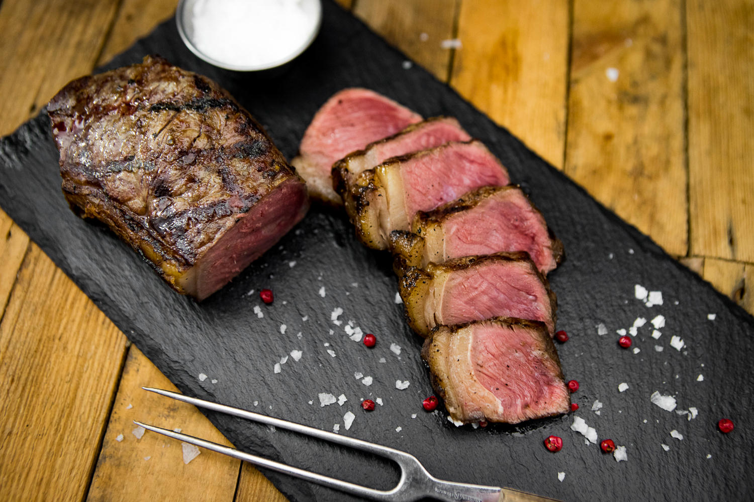 Dry Aged Roastbeef am Stück vom Oberpfalz-Rind – Premium Rindfleisch kaufen T-Bone-Steak Dry Aged vom Oberpfalz-Rind auf Holzbrett angerichtet, mit kräftiger Marmorierung und natürlicher Fettkante, saftig gebraten, umgeben von Gewürzen und Kräutern, hochwertige Fleischqualität in rustikalem Ambiente.