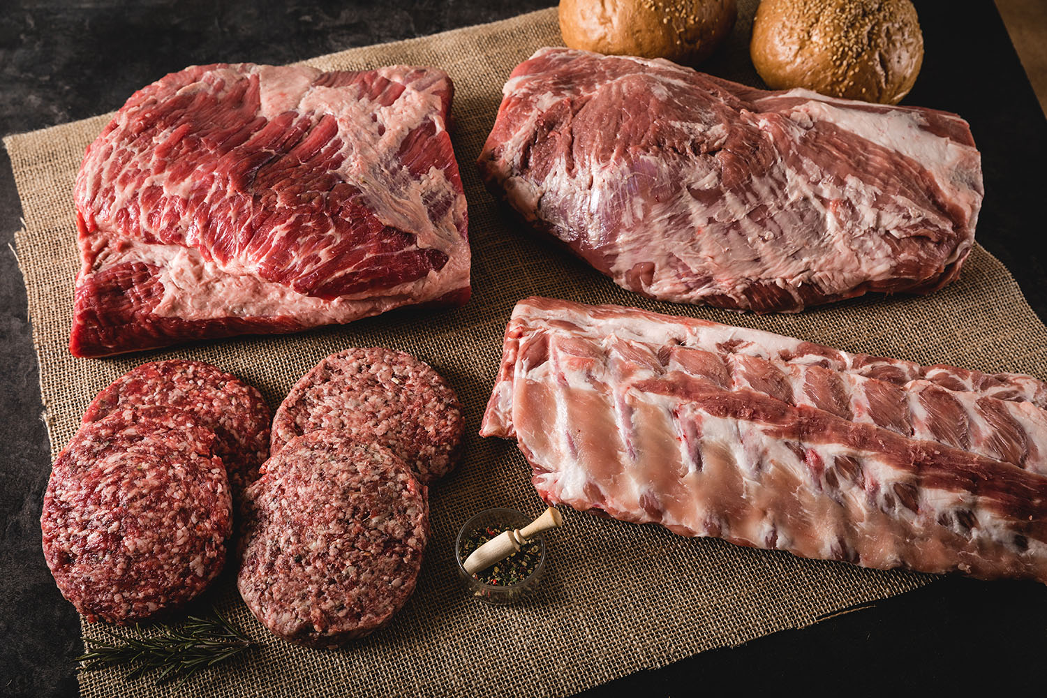 Mega BBQ Party Paket mit hochwertigem Grillfleisch für deine Grillfeier Grillpaket mit verschiedenen Fleischsorten auf Holzbrett: saftige Rindersteaks, Spareribs, Würstchen, Grillgemüse und Maiskolben, angerichtet mit BBQ-Saucen und Kräutern – ideal für Sommer-Grillparty oder Mega-BBQ.