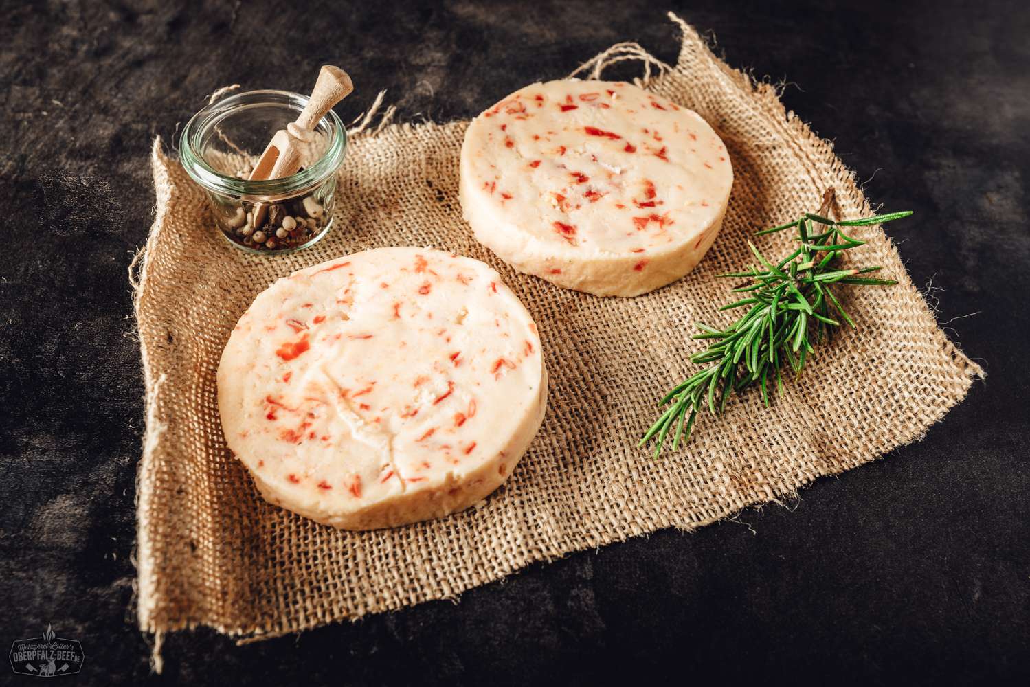Gegrillter Käse mit Peppadew – Vegetarische Grillalternative aus der Oberpfalz Grillkäse mit Chili in rechteckiger Form, goldbraun gegrillt, mit sichtbaren roten Chilistückchen auf der Oberfläche, serviert auf einem dunklen Holzteller mit frischen Kräutern garniert – ideal für vegetarisches Grillen und scharfes BBQ.