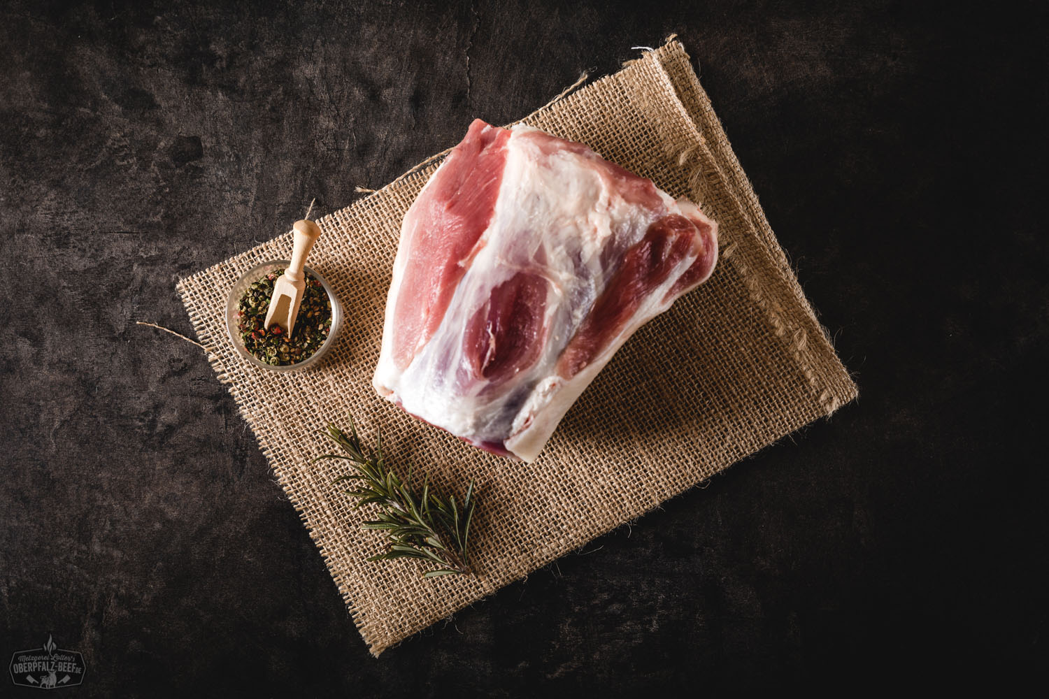 Hintere Haxe vom Oberpfälzer Landschwein – frisch, regional und qualitativ hochwertig Rohes Stück hintere Schweinshaxe vom Oberpfälzer Landschwein, mager und gut durchzogen, auf dunklem Untergrund mit Kräutern und Gewürzen angerichtet – frisches, regionales Fleisch geeignet für traditionelle Schmorgerichte.