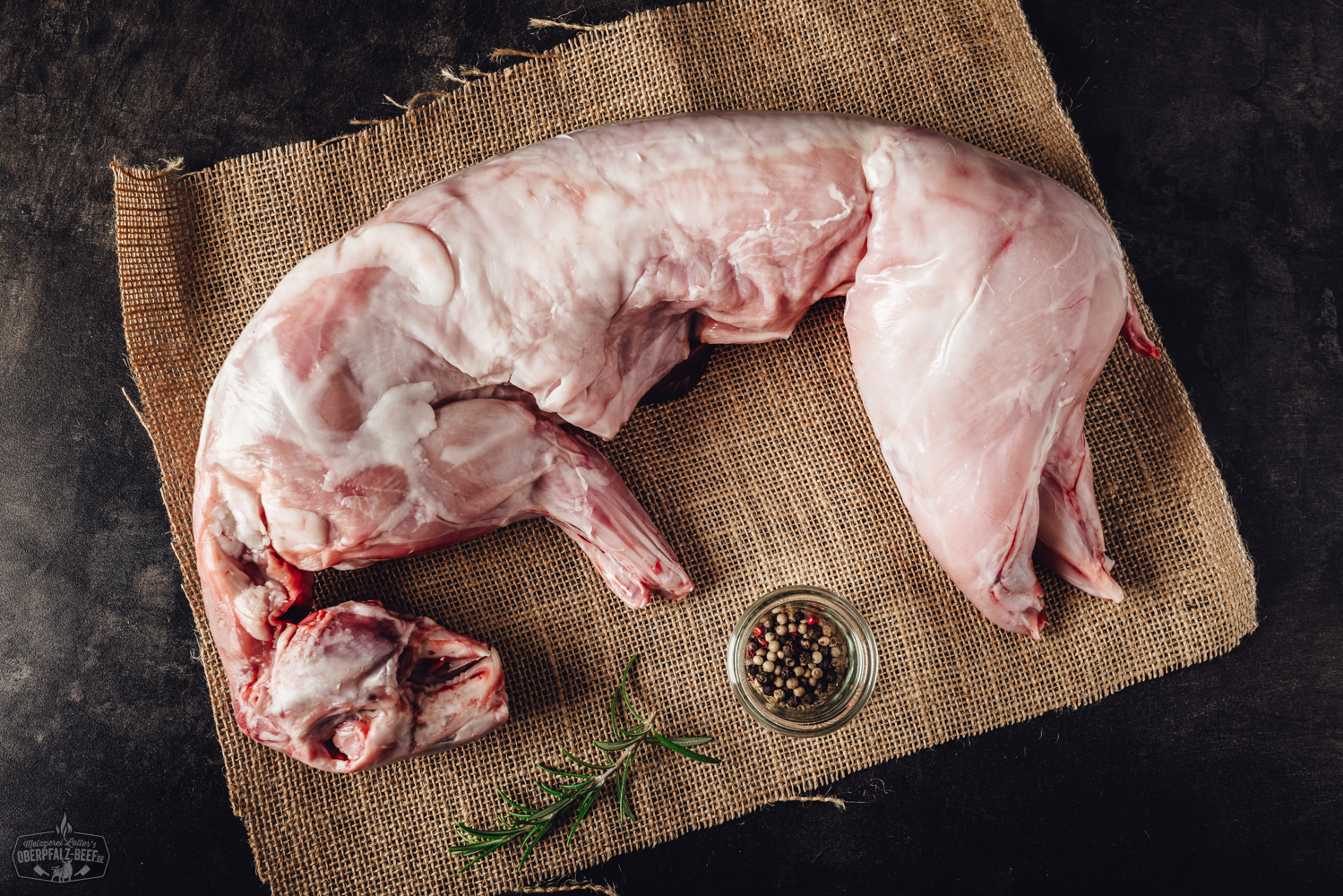 Kaninchenfleisch Angebot Oberpfalz Beef Bild Kaninchenfleisch auf einem Holzbrett platziert, umgeben von frischen Kräutern, bereit für eine Zubereitung. Frisches, hochwertiges Kaninchenfleisch, ideal für gesunde Rezepte und Gourmetgerichte in der Küche.