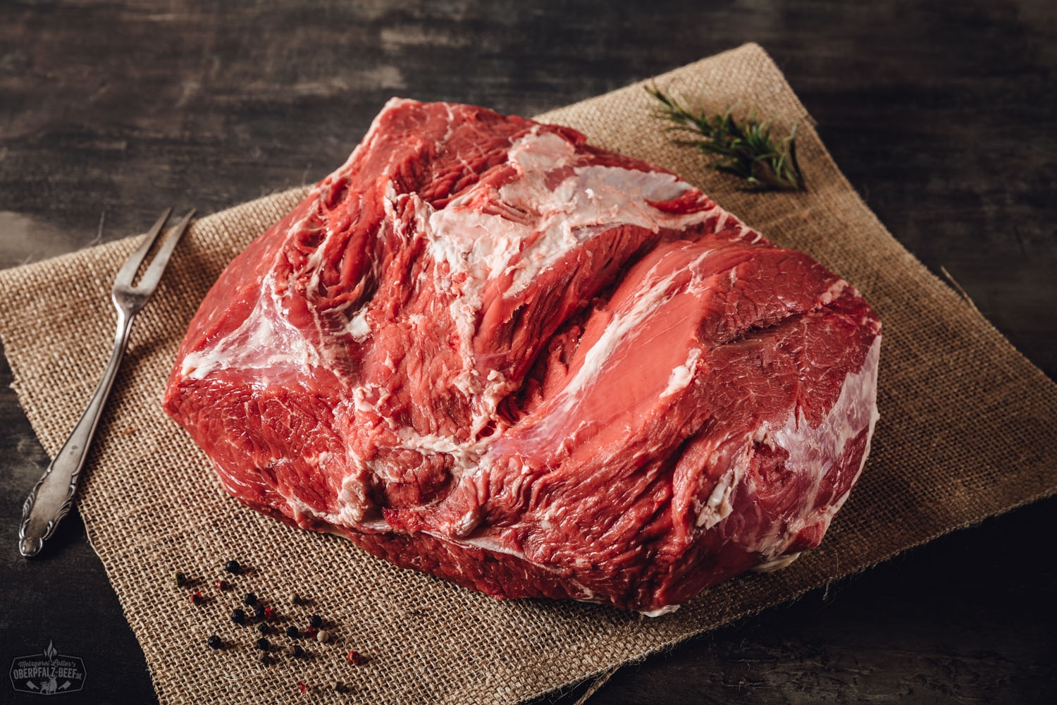 Rohes Stück Steakhüfte vom Oberpfalz-Rind auf dunklem Untergrund, fein marmoriert, Wet-Aged, mit sichtbarer Maserung und kräftiger roter Farbe – hochwertiges Rindfleisch für Steakliebhaber.