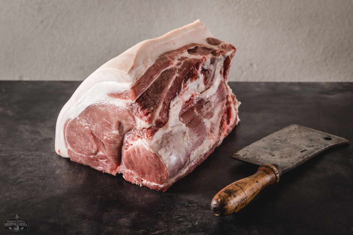 Frisches halbes Kotelett vom Oberpfälzer Landschwein im Filetcut, roh und saftig mit zarter Marmorierung auf dunklem Untergrund, ideal für Grill oder Pfanne.