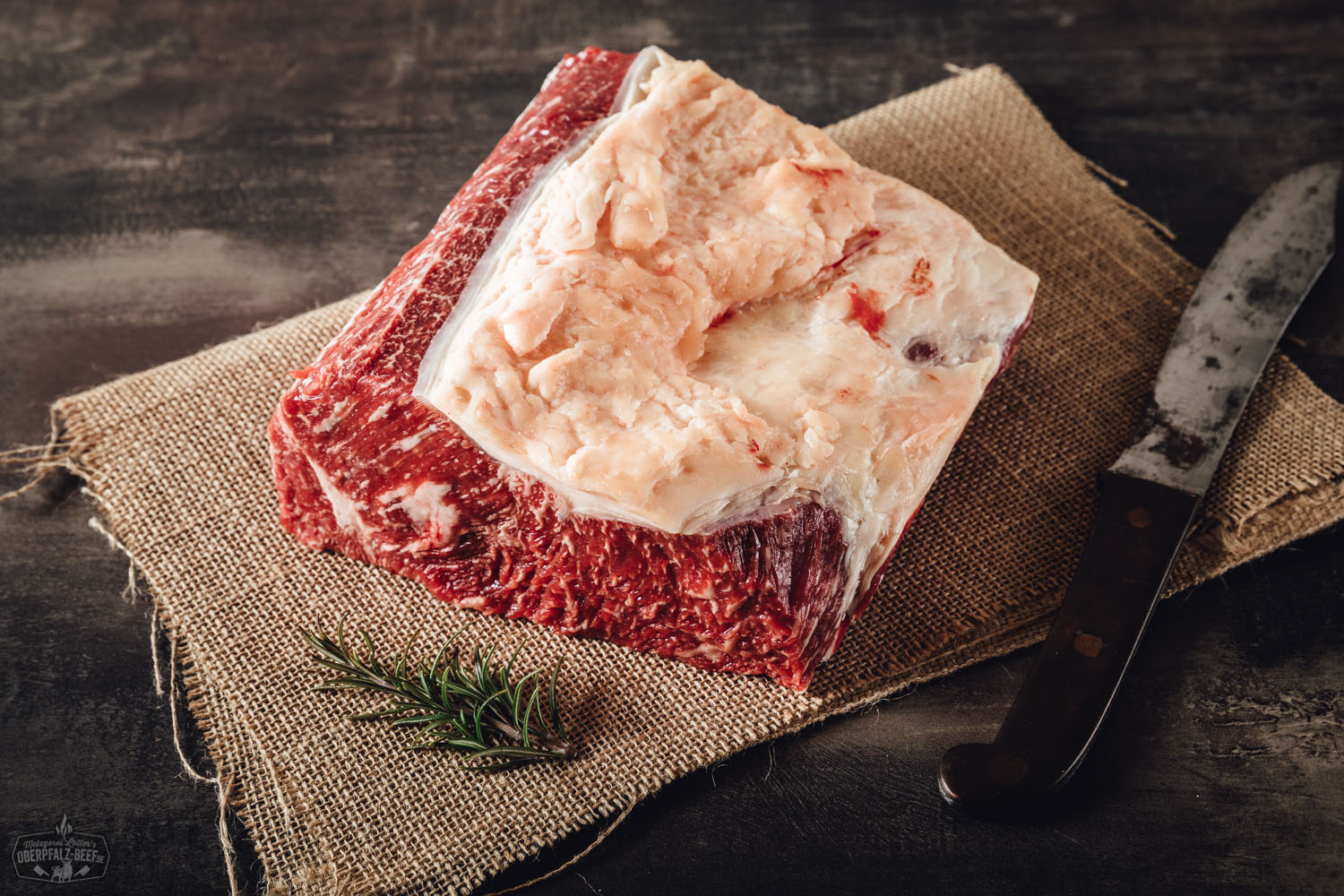 Roastbeef am Stück – Wet Aged vom Oberpfalz-Rind in Premium-Qualität Roastbeef Steak vom Rind, medium gebraten, aufgeschnitten und saftig rosa im Inneren, auf einem dunklen Holzbrett angerichtet, daneben grobes Meersalz, Pfeffer und frische Rosmarinzweige – hochwertiges Rindfleisch in rustikaler Präsentation.