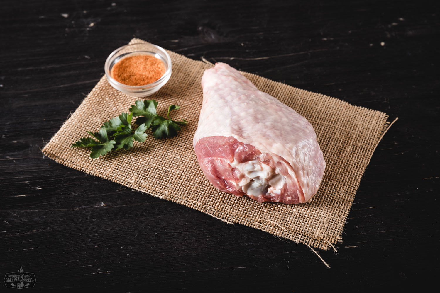 Rohe Unterkeulen von der Oberpfälzer Bauernpute auf dunklem Naturstein angerichtet, mit Thymian, Rosmarin und grobem Meersalz garniert – frisches Geflügel direkt vom Bauernhof.