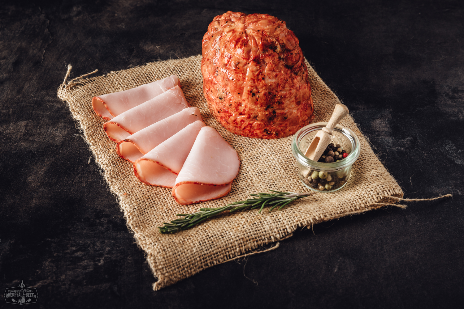 Geschnittene Scheiben von Pfefferschinken auf einem Holzbrett angerichtet, mit frischer Petersilie garniert; hochwertige Delikatesse aus der Oberpfalz – ideal für Brotzeit oder Antipasti.