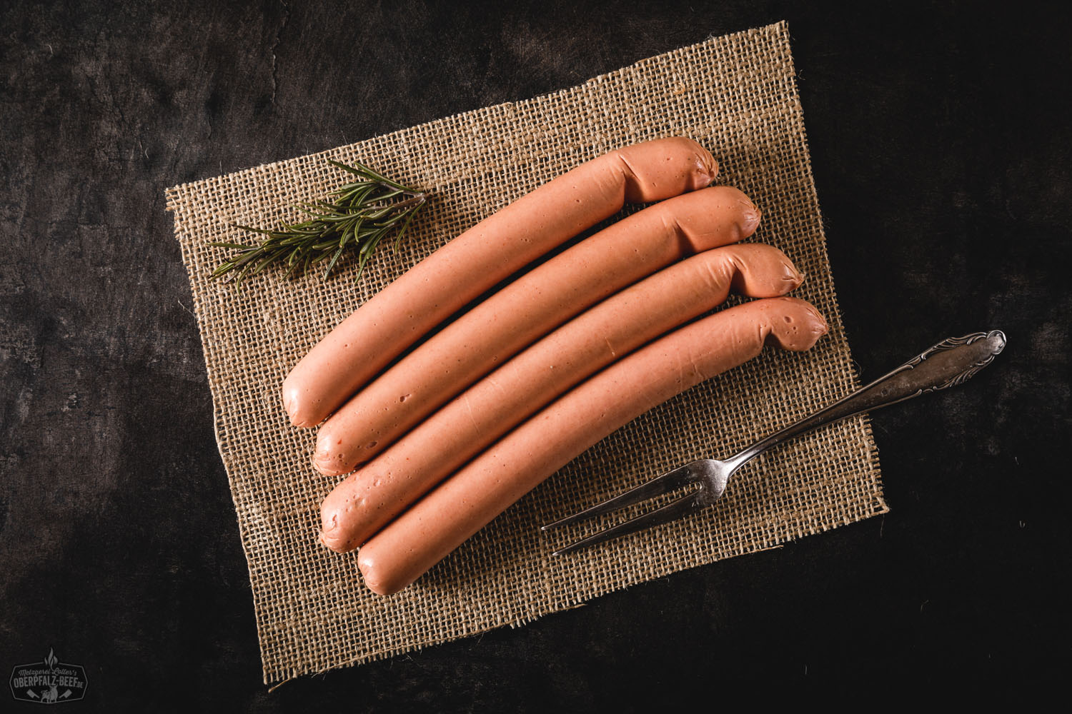 Nahaufnahme eines frisch zubereiteten Hot Dogs mit Brötchen, saftigem Würstchen, Röstzwiebeln, Gurkenscheiben und würzigem Senf, serviert auf einem Holzbrett – deftiges Streetfood mit Fokus auf bayerische Fleischqualität.