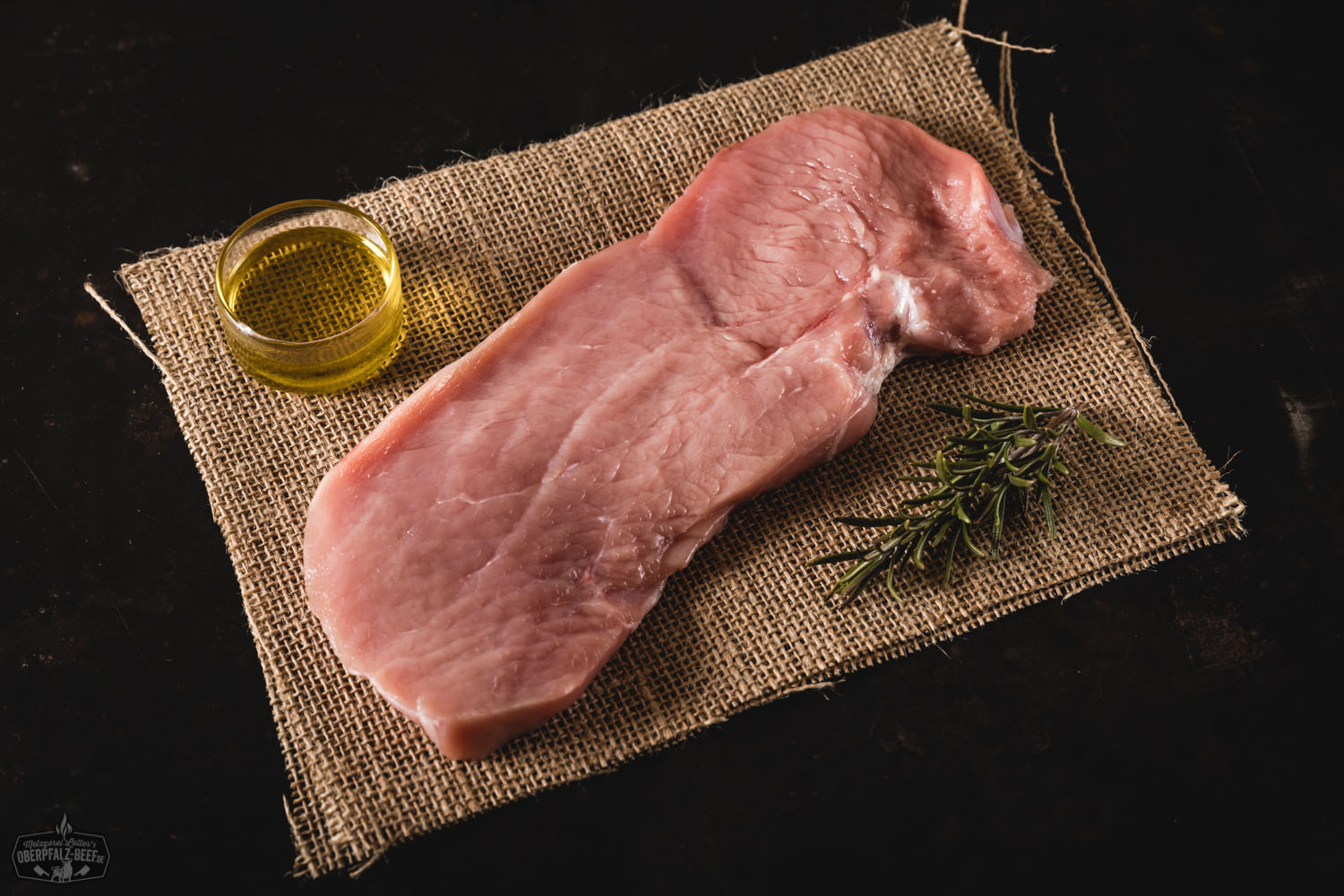 Schnitzel vom Oberpfälzer Milchkalb – zartes Kalbfleisch regional genießen Goldbraun gebratenes Kalbsschnitzel vom Oberpfälzer Milchkalb auf einem weißen Teller, serviert mit Zitronenscheibe und grüner Kräutergarnitur, angerichtet auf rustikalem Holztisch – hochwertige Nahaufnahme zur Darstellung regionaler Fleischspezialitäten.