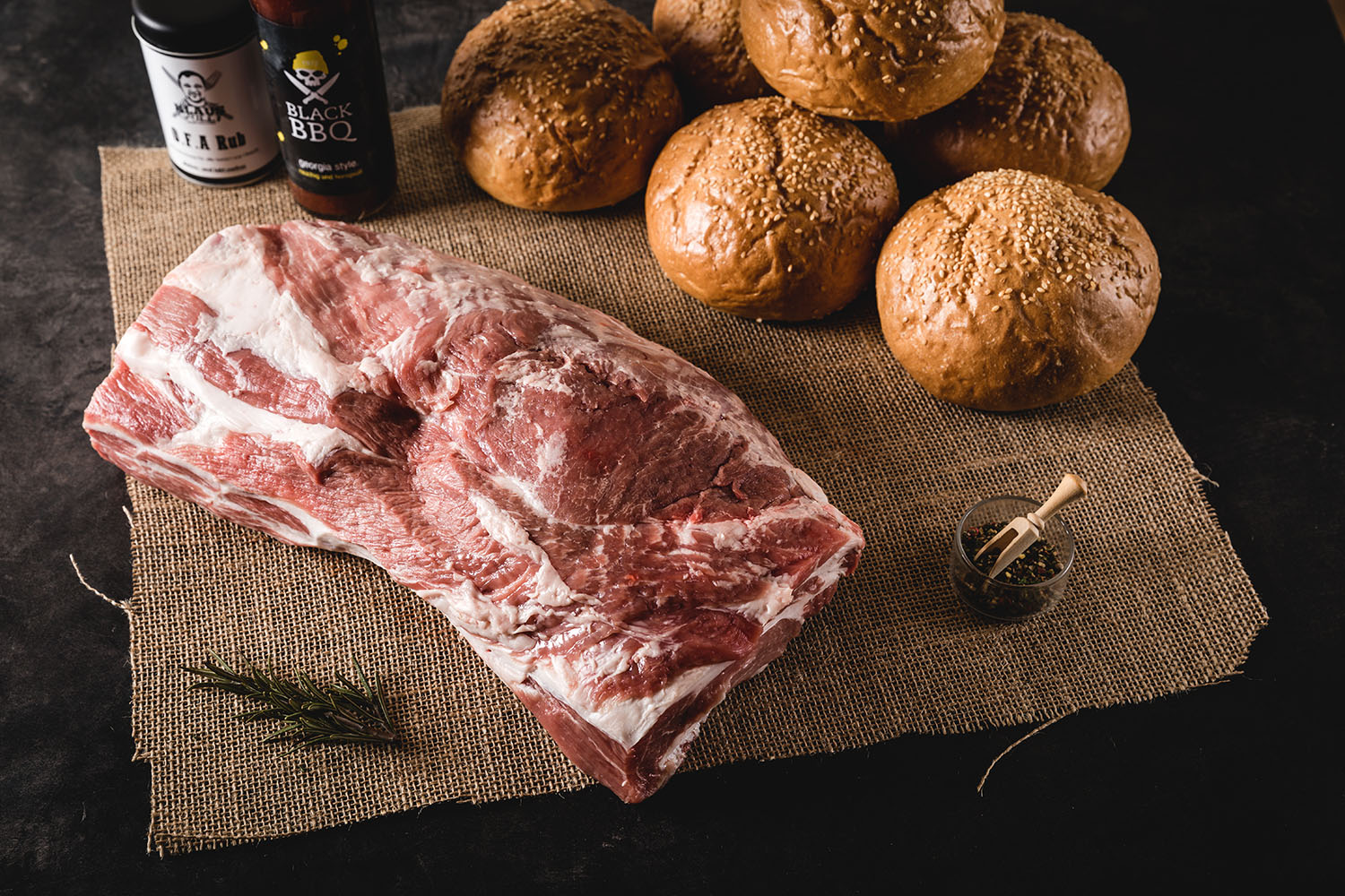 Pulled Pork Paket – Zartes BBQ-Fleisch aus der Oberpfalz kaufen Pulled Pork Paket von Oberpfalz Beef auf Holzuntergrund: Vakuumverpacktes, fertig gegartes Pulled Pork in aromatischer BBQ-Soße vor Grillbesteck und Gewürzen, ideal für Burger, Sandwiches oder BBQ-Gerichte.