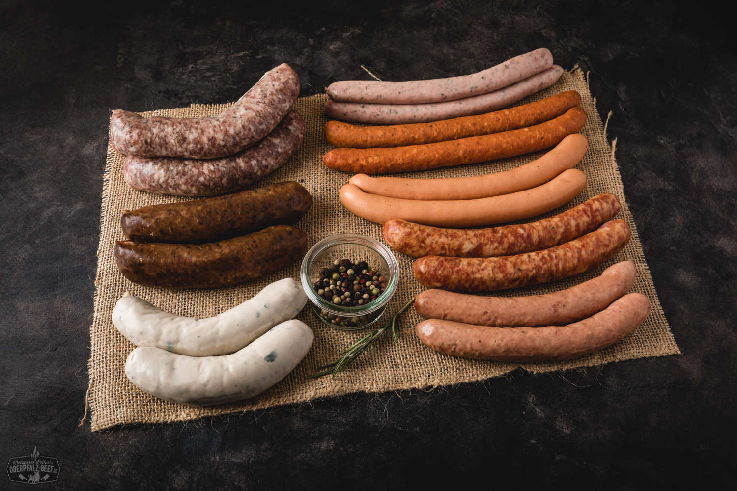 Oberpfälzer Würstchenparade – Auswahl regionaler Bratwürste und Grillwurst vom Metzger Verschiedene Oberpfälzer Wurstspezialitäten, darunter Bratwürste, Wiener und Knacker, dekorativ auf einem rustikalen Holzbrett mit Senf, frischen Kräutern und Brot angerichtet – traditionelles Wurstpaket von Oberpfalz Beef.
