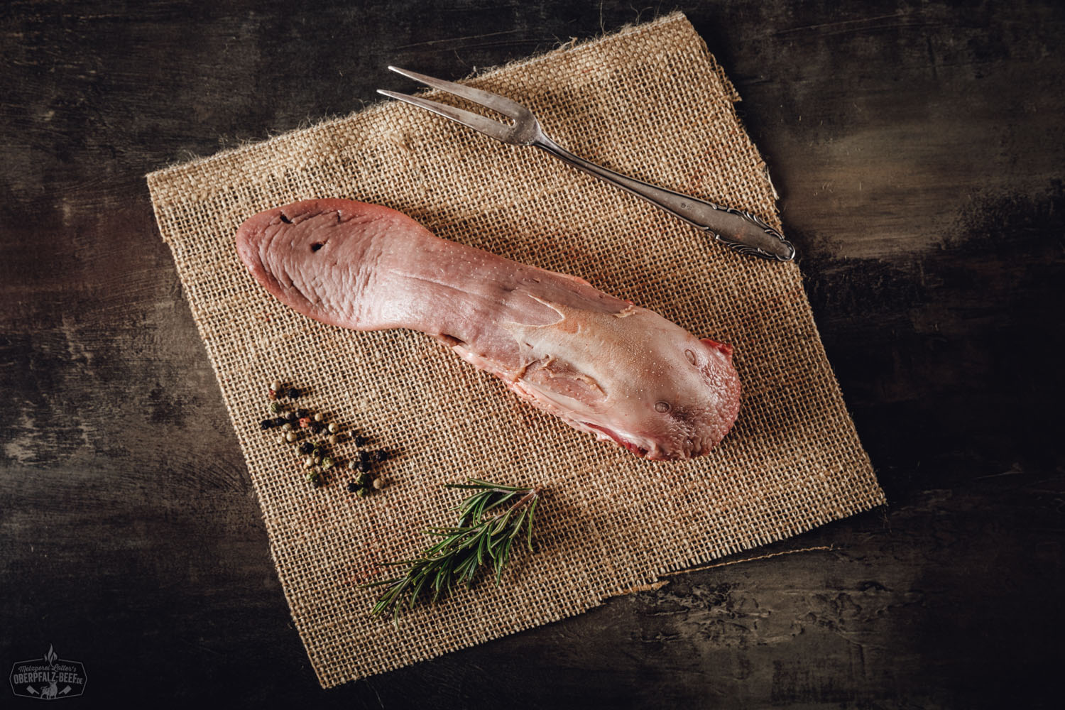 Frische rohe Schweinezunge auf Holzbrett – hochwertiges Metzgerfleisch aus Bayern Schweinezunge auf einem weißen Hintergrund, frisch zubereitet und servierbereit auf einem Holzbrett, perfekt für Feinschmecker und Liebhaber hochwertiger Fleischspezialitäten.