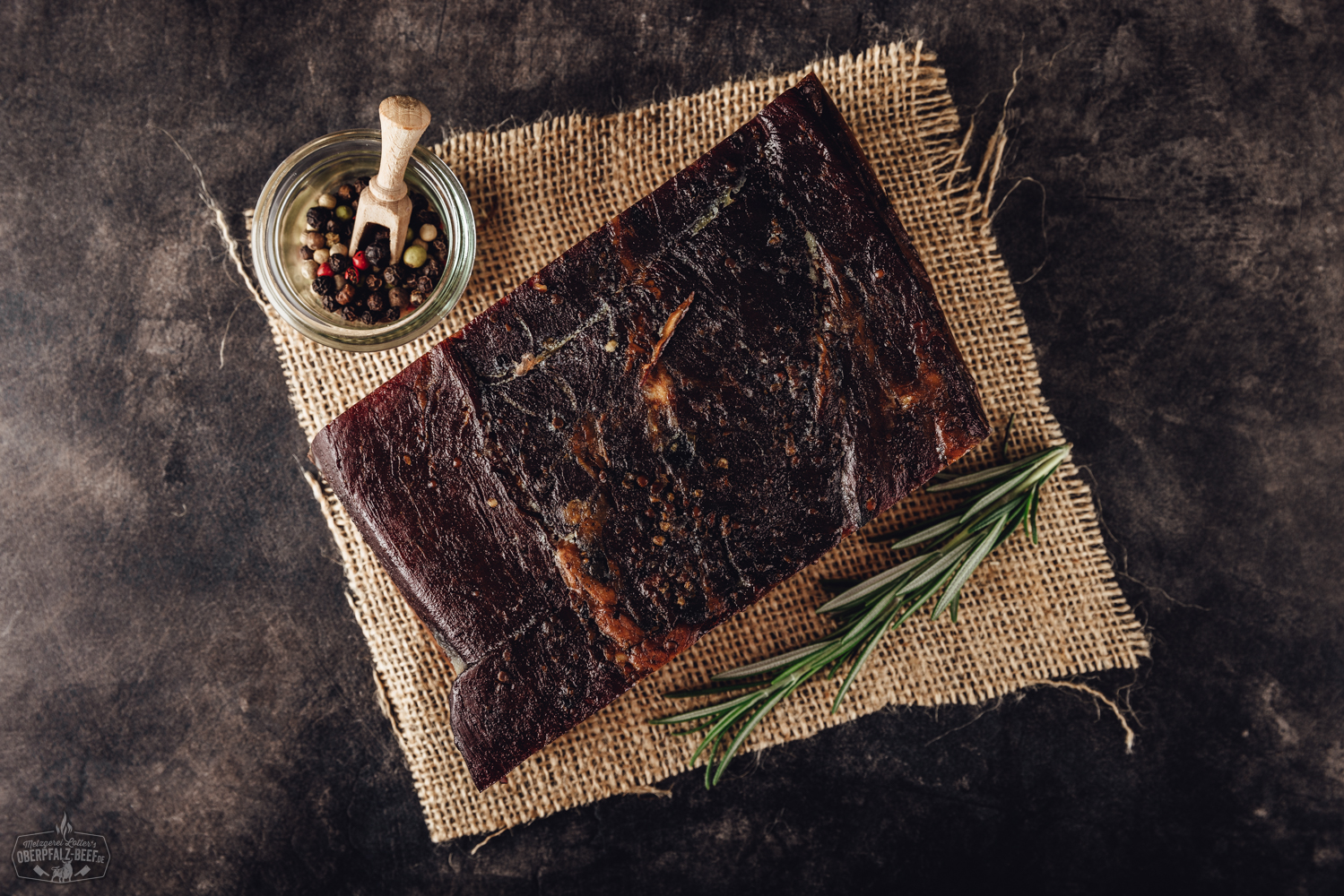 Oberpfälzer Bauernschinken aus der Hüfte am Stück auf einem Holztisch präsentiert, ideal für Liebhaber traditioneller bayerischer Fleischspezialitäten.
