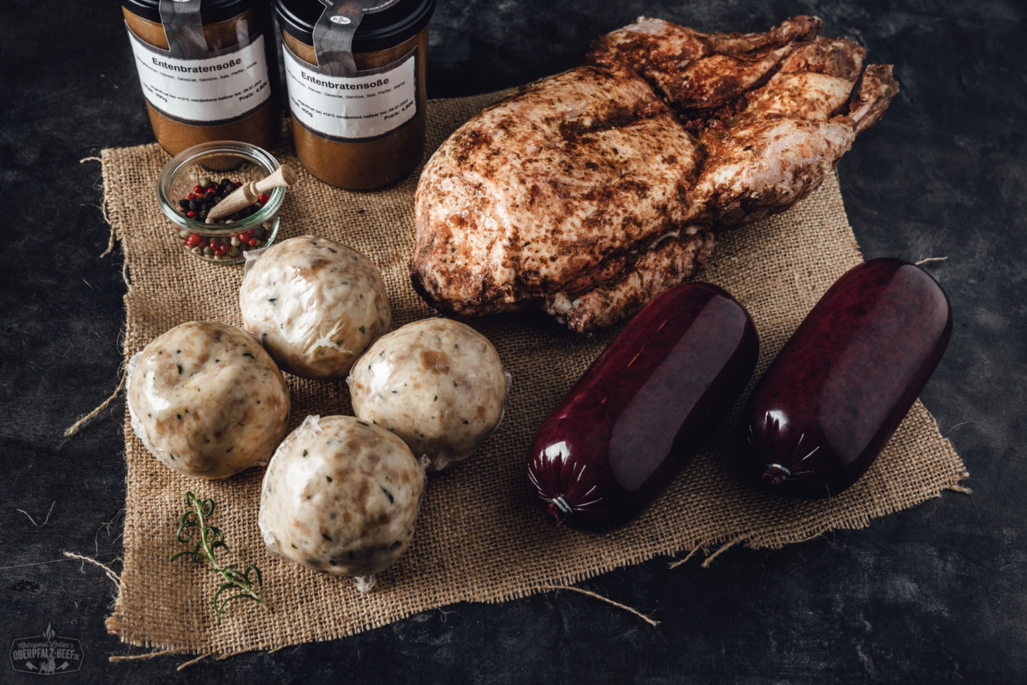 Holzbox mit zwei vakuumverpackten, küchenfertigen Entenhälften auf Strohbett, beigelegt ein Flyer mit „Oberpfälzer Entenbox“-Logo; rustikale Präsentation für hochwertigen Entenbraten, ideal fürs Weihnachtsfest.