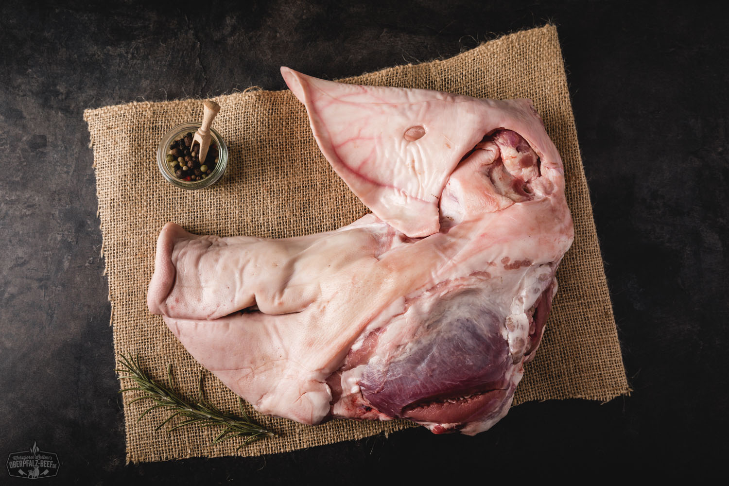 Frischer halber Schweinekopf vom Oberpfälzer Landschwein – regional & nachhaltig Frischer halber Schweinekopf vom Oberpfälzer Landschwein auf dunklem Untergrund, roh und sauber zugeschnitten, Fleischstruktur und Haut deutlich erkennbar – regionale Fleischspezialität für traditionelle Zubereitungen.