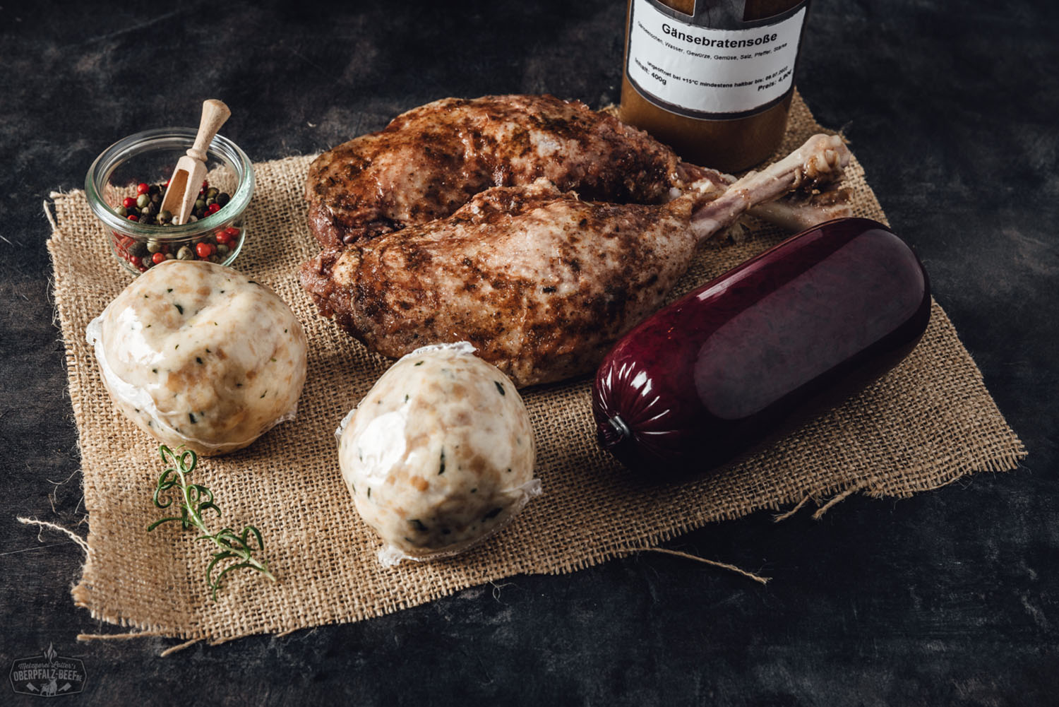 Oberpfälzer Gänsebox mit knuspriger Gänsekeule und Beilagen – Festessen online bestellen Zubereitete Gänsekeule mit knuspriger Haut auf einer rustikalen Holzplatte, serviert mit Kartoffelknödeln, Blaukraut und einer dunklen Bratensoße – traditionelle Oberpfälzer Spezialität festlich angerichtet.