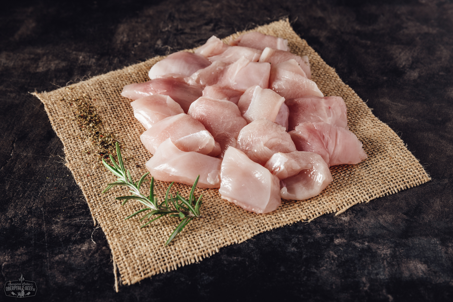 Handgeschnittenes Fondue-Fleisch aus Hähnchenbrust, roh und in gleichmäßige Streifen geschnitten, frisch angerichtet auf einem hellen Teller mit Kräutergarnitur – ideales zartes Geflügelfleisch für Fondue oder asiatische Gerichte.