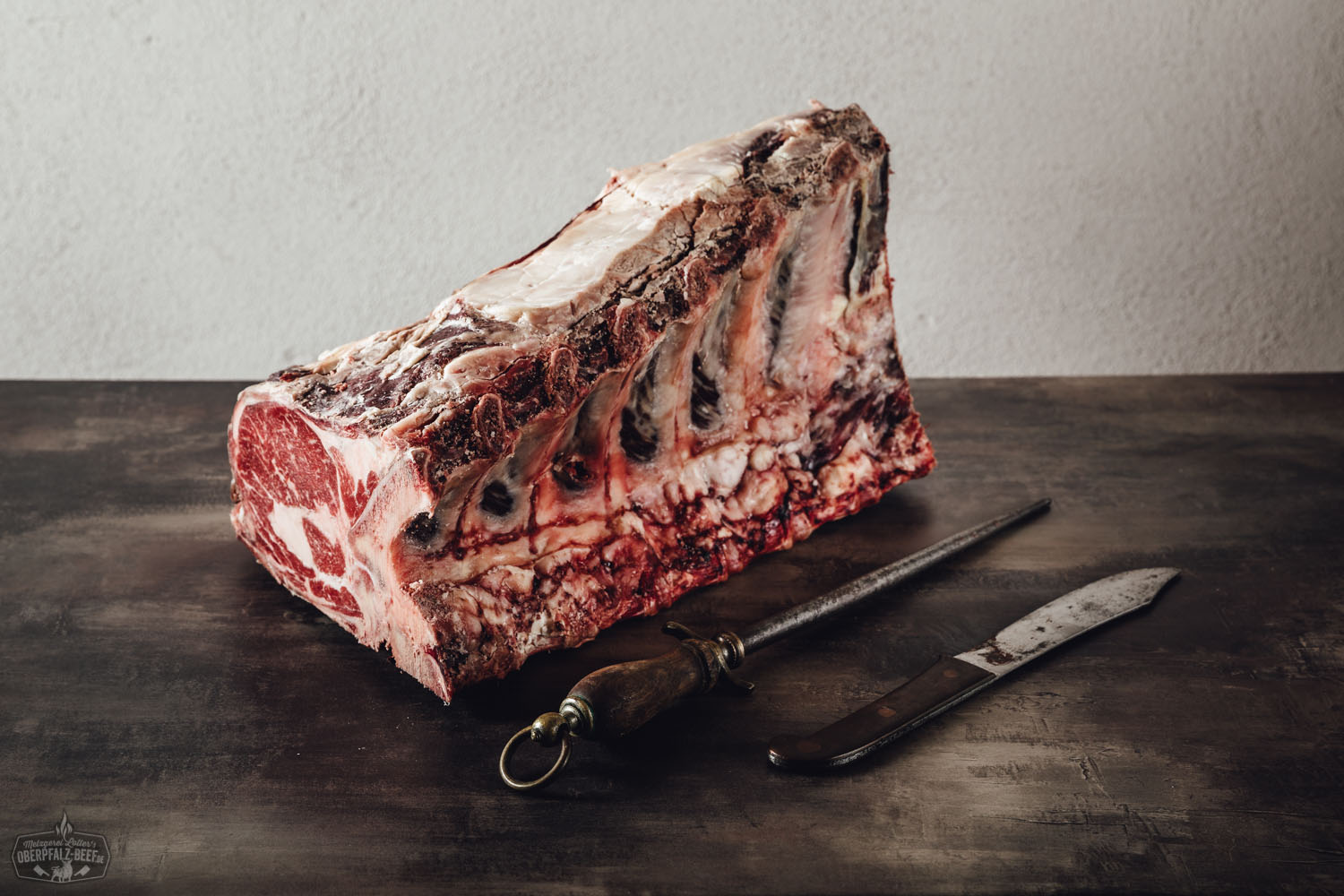 Dry-aged Cote de Boeuf (Rib-Eye) am Stück vom Oberpfalz-Rind auf dunklem Holzbrett, mit sichtbarer Marmorierung und Knochen, hochwertig präsentiert für Premium-Rindfleischgenuss.