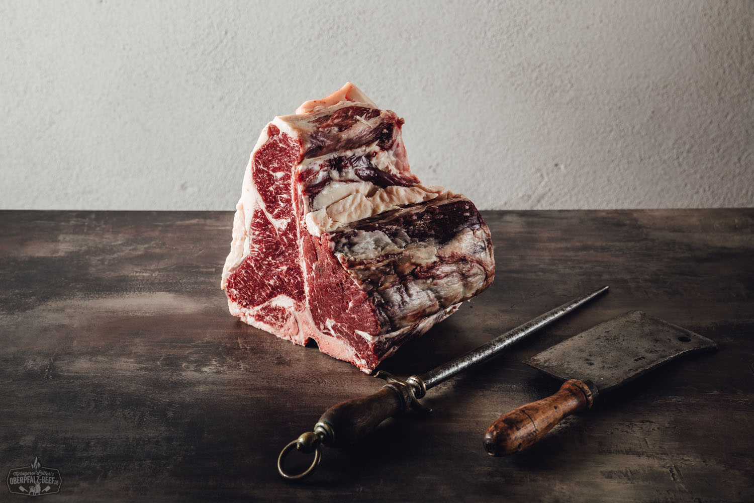 Rohes Porterhouse-Steak vom Oberpfalz-Rind auf dunklem Untergrund, gut marmoriert mit sichtbarem Knochen, präsentiert zum Selberreifen – hochwertiger Zuschnitt für Dry Aged Beef direkt vom regionalen Erzeuger.