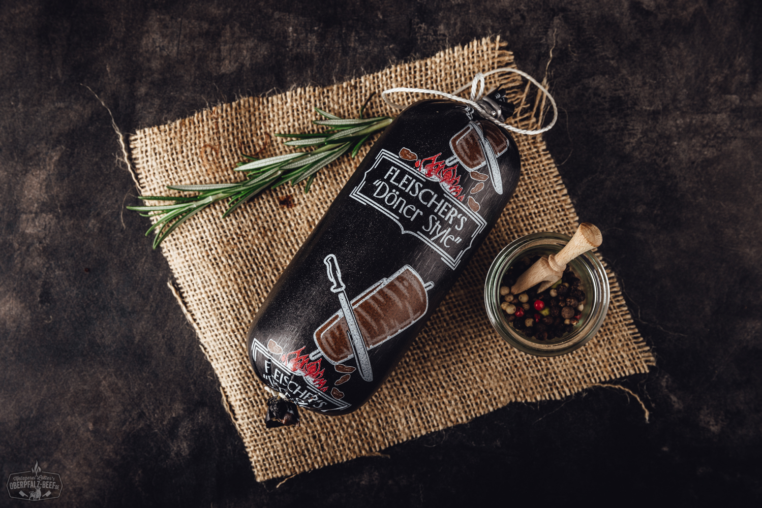 Dönerwurst vom Grill – Herzhaft gewürzt und perfekt gebräunt Nahaufnahme einer knusprig gebratenen Dönerwurst aus hochwertigem Rindfleisch auf einem dunklen Holzbrett, daneben rustikale Brotstücke, rote Zwiebeln und frische Kräuter – deftige Spezialität aus der Oberpfalz, ideal für Grillfans und Fleischliebhaber.