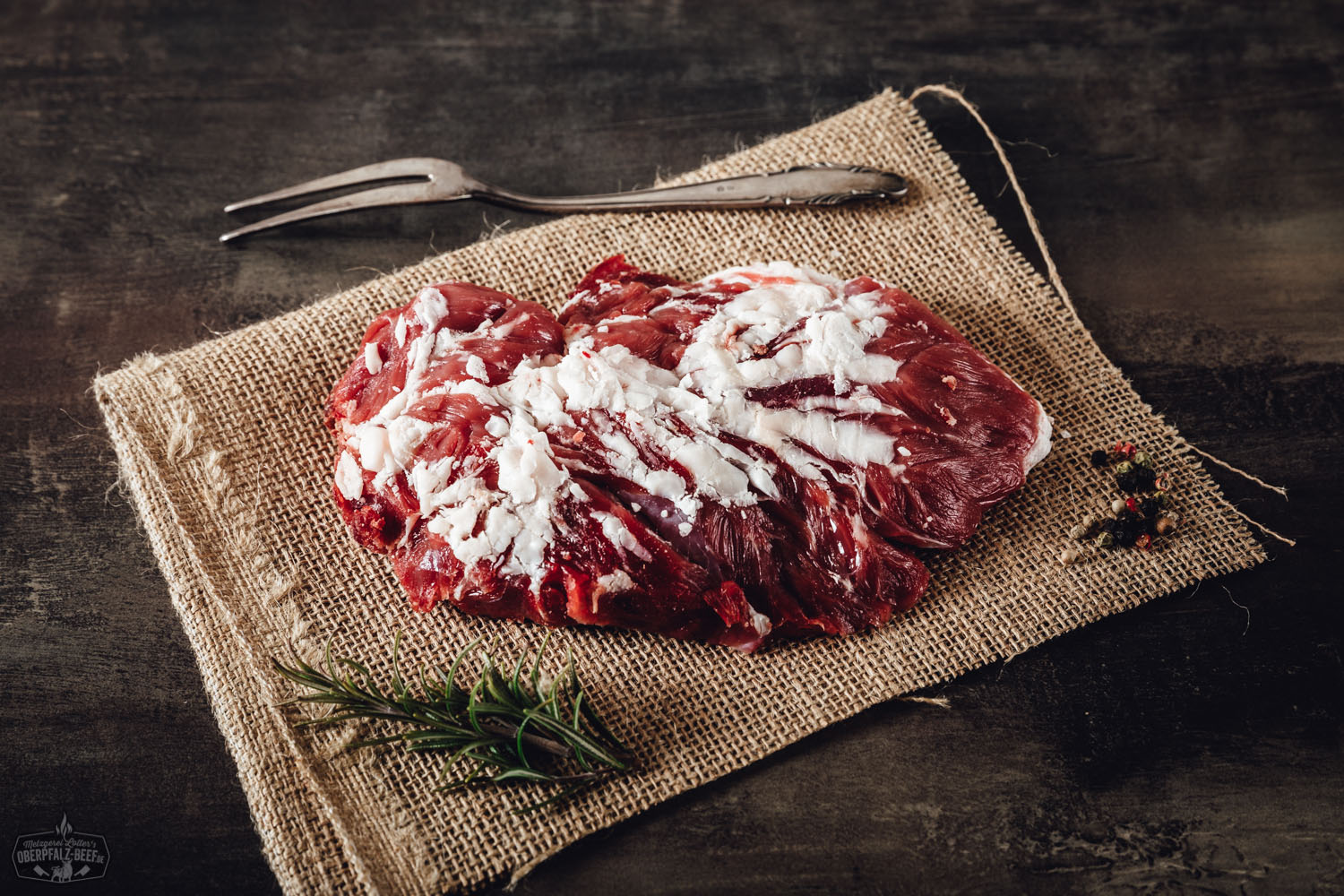 Rohes Spider Steak vom Oberpfalz-Rind, wet-aged gereift, mit feiner Marmorierung und auffälliger fächerförmiger Muskelstruktur, auf dunklem Untergrund angerichtet – hochwertiges Rindfleisch für Fleischliebhaber.