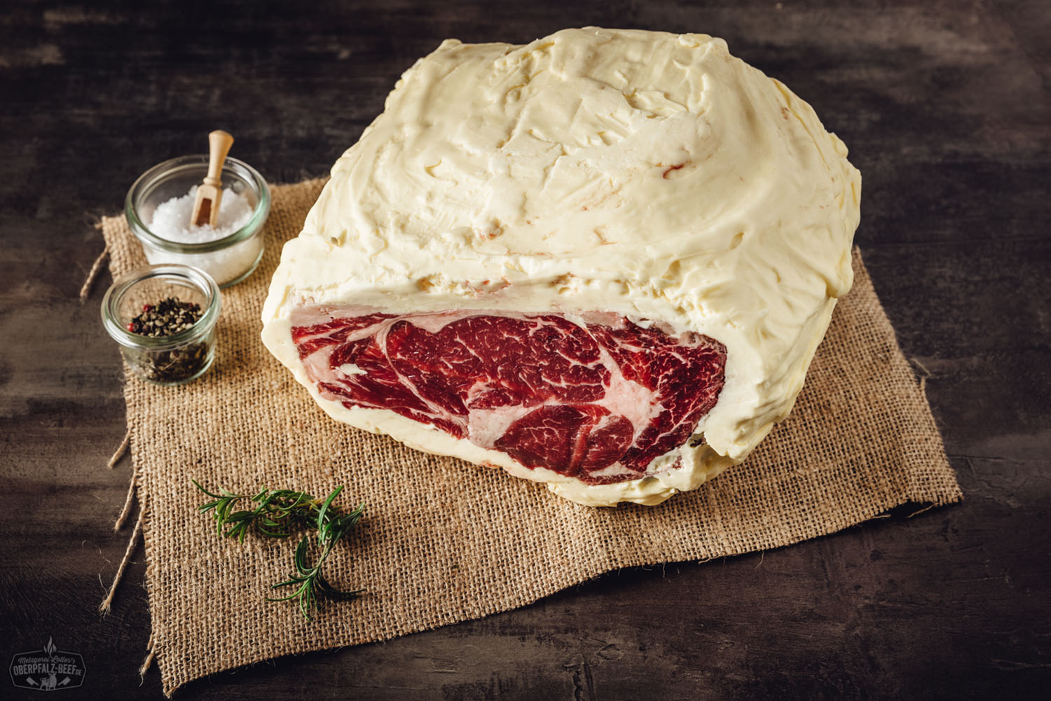 Entrecôte Rib-Eye am Stück – Butter Aged vom Oberpfalz-Rind Entrecôte vom Oberpfalz-Rind am Stück auf Holzbrett – dry aged mit Butterreifung, gut marmoriertes Rib-Eye-Steak mit kräftiger Fettmaserung, roh und küchenfertig, vor dunklem Hintergrund inszeniert.