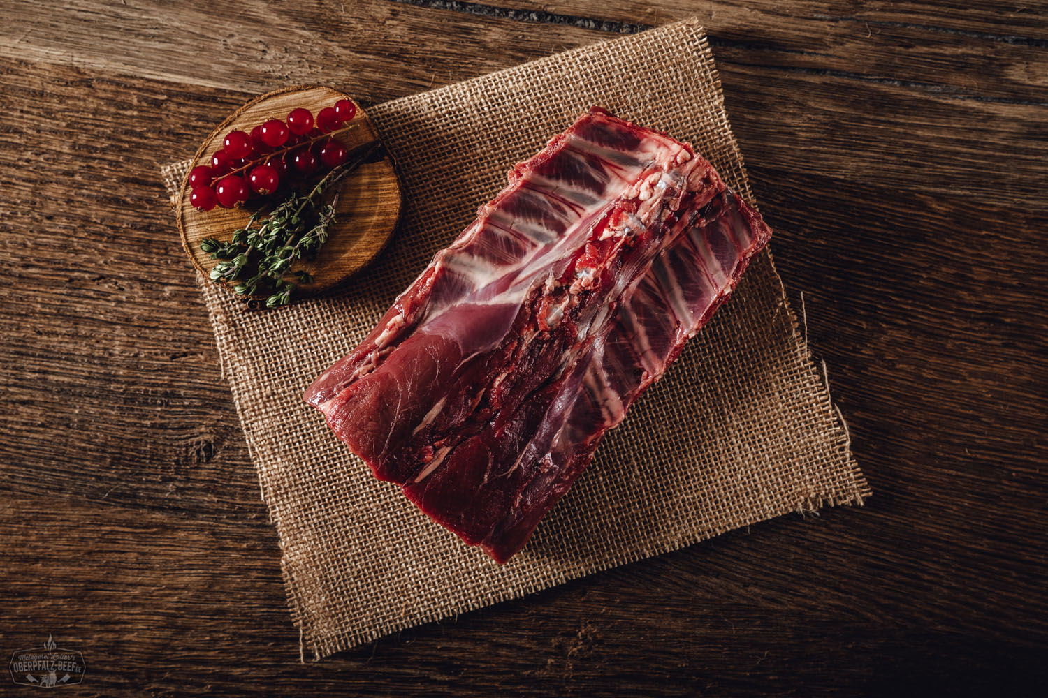 Rücken mit Knochen vom Oberpfälzer Reh auf Holzbrett mit zartem Wildfleisch, frischen Kräutern und natürlicher Waldatmosphäre. Perfekt für Wildliebhaber und Gourmetgerichte.