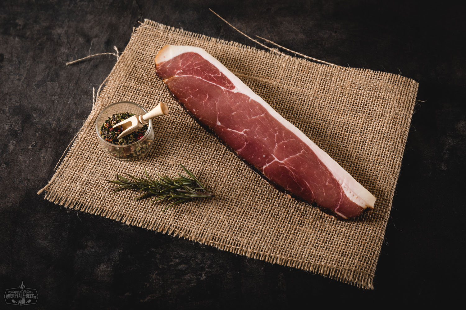 Oberpfälzer Bauern-Geräuchertes aus dem Schlegel auf Brotzeitscheibe – Traditionelle Wurstspezialität Traditionelle Brotzeitscheibe mit Oberpfälzer Bauern-Geselchtem aus dem Schlegel auf Holzbrett, serviert mit Gewürzgurke, frischem Bauernbrot und rustikaler Dekoration – typisch bayerische Spezialität.