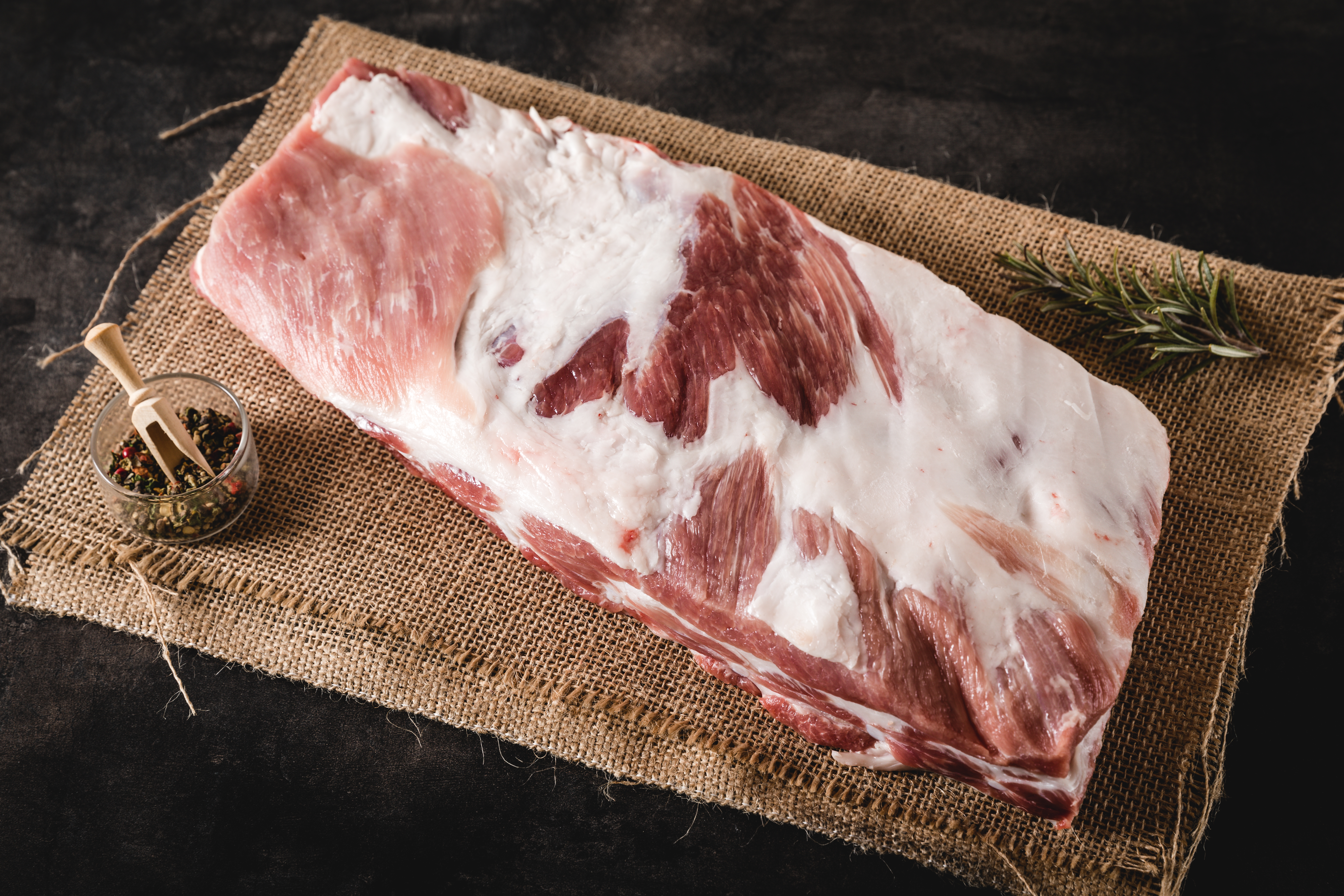Schwein auf der Weide mit Oberpfalz Beef Qualitätssiegel Frische Schweinekarree-Steaks auf einem bearbeiteten Holzbrett, perfekt für den Grill oder das Braten in der Pfanne. Qualitativ hochwertiges Oberpfalz-Beef Fleisch.