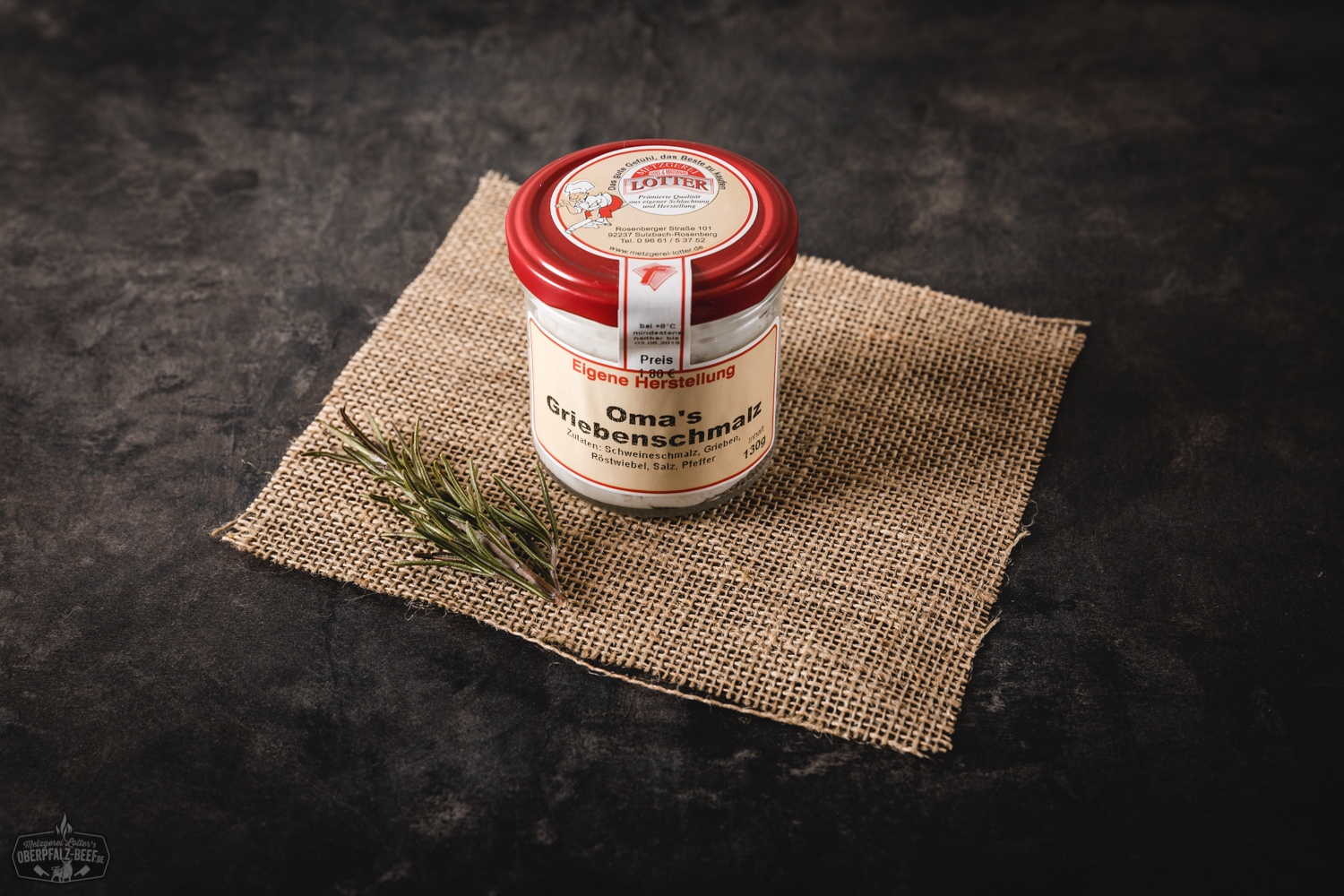 Ein Glas mit traditionellem Griebenschmalz, gefüllt mit goldgelben Zwiebelstückchen und knusprigen Schweinegrieben, angerichtet auf einem rustikalen Holztisch.