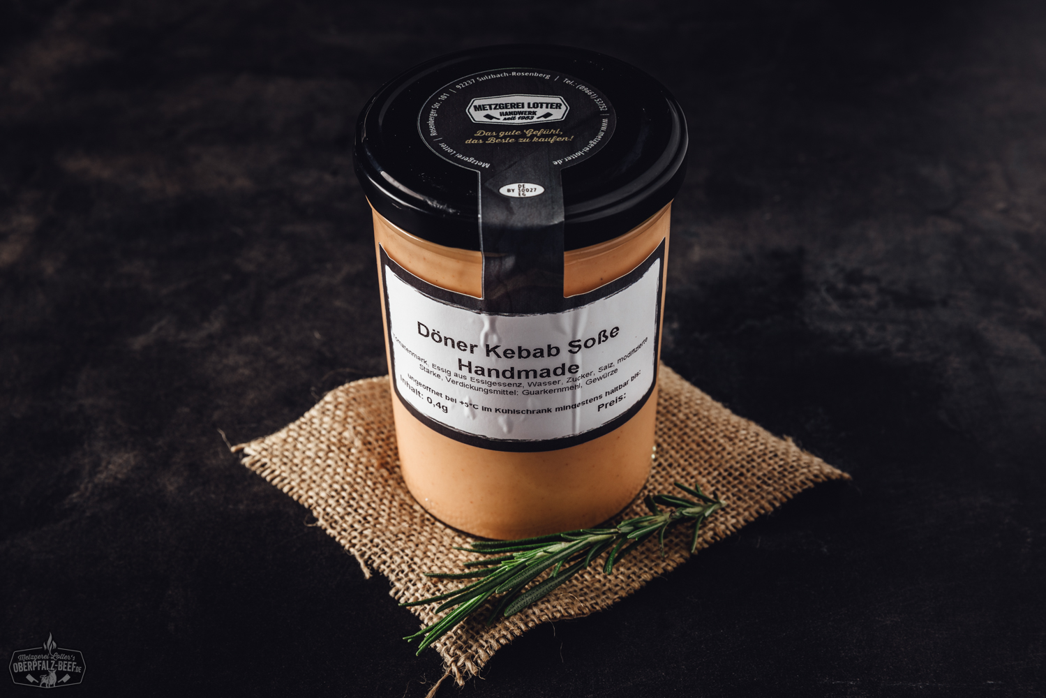 Frisches, handgemachtes Zaziki in einer weißen Schale, garniert mit einem Zweig frischer Petersilie, daneben frische Gurkenscheiben und Knoblauchzehen auf einem dunklen Holzuntergrund – cremiger Joghurt-Dip typisch für die griechische Küche.