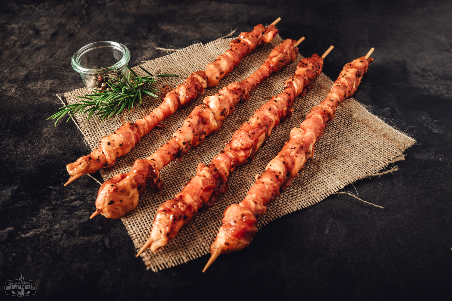 BBQ-Soße "Hot" von Oberpfalz Beef in Glasflasche mit rotem Etikett, stehend auf dunklem Untergrund; daneben frische Chilis, Knoblauch und Gewürze – scharfe Barbecue-Sauce für Grillgerichte.
