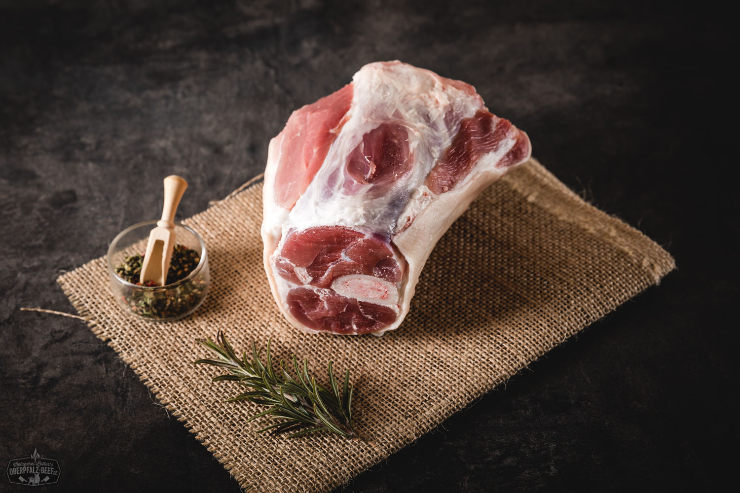 Hintere Haxe vom Oberpfälzer Landschwein – frisch, regional und qualitativ hochwertig Rohes Stück hintere Schweinshaxe vom Oberpfälzer Landschwein, mager und gut durchzogen, auf dunklem Untergrund mit Kräutern und Gewürzen angerichtet – frisches, regionales Fleisch geeignet für traditionelle Schmorgerichte.