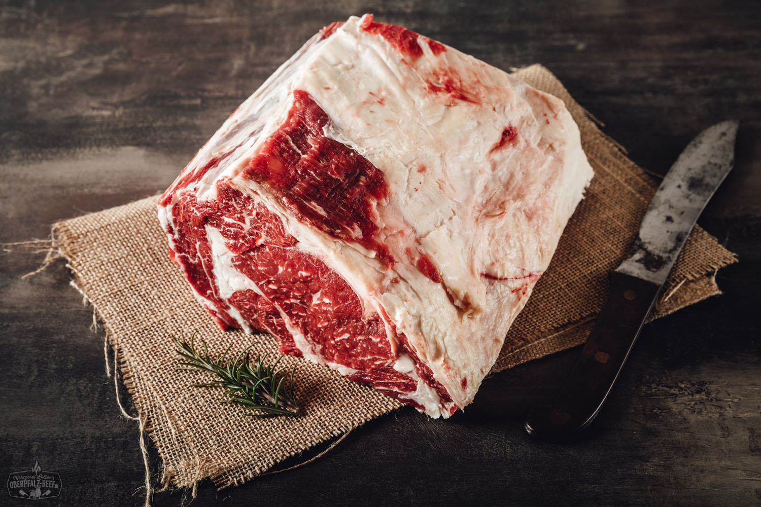Rohes Entrecôte-Rib-Eye-Steak ohne Knochen vom Oberpfalz-Rind auf schwarzem Untergrund, mit sichtbarer feiner Marmorierung und Fettdeckel – hochwertige Fleischqualität zum Selbstreifen.