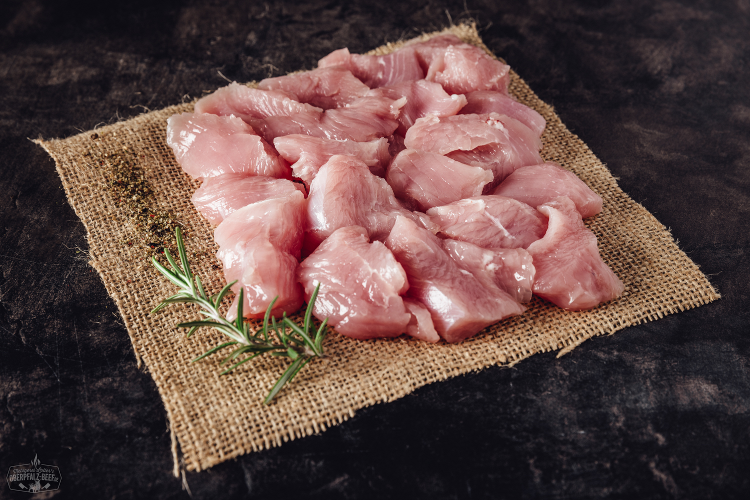 Nahaufnahme von zart rosa geschnittenem Putenbrust-Fleisch für Fondue, sorgfältig per Hand geschnitten und auf einem dunklen Teller angerichtet, mit dezentem Lichteinfall, ideal für ein festliches Essen oder gesellige Fleischfondue-Abende.