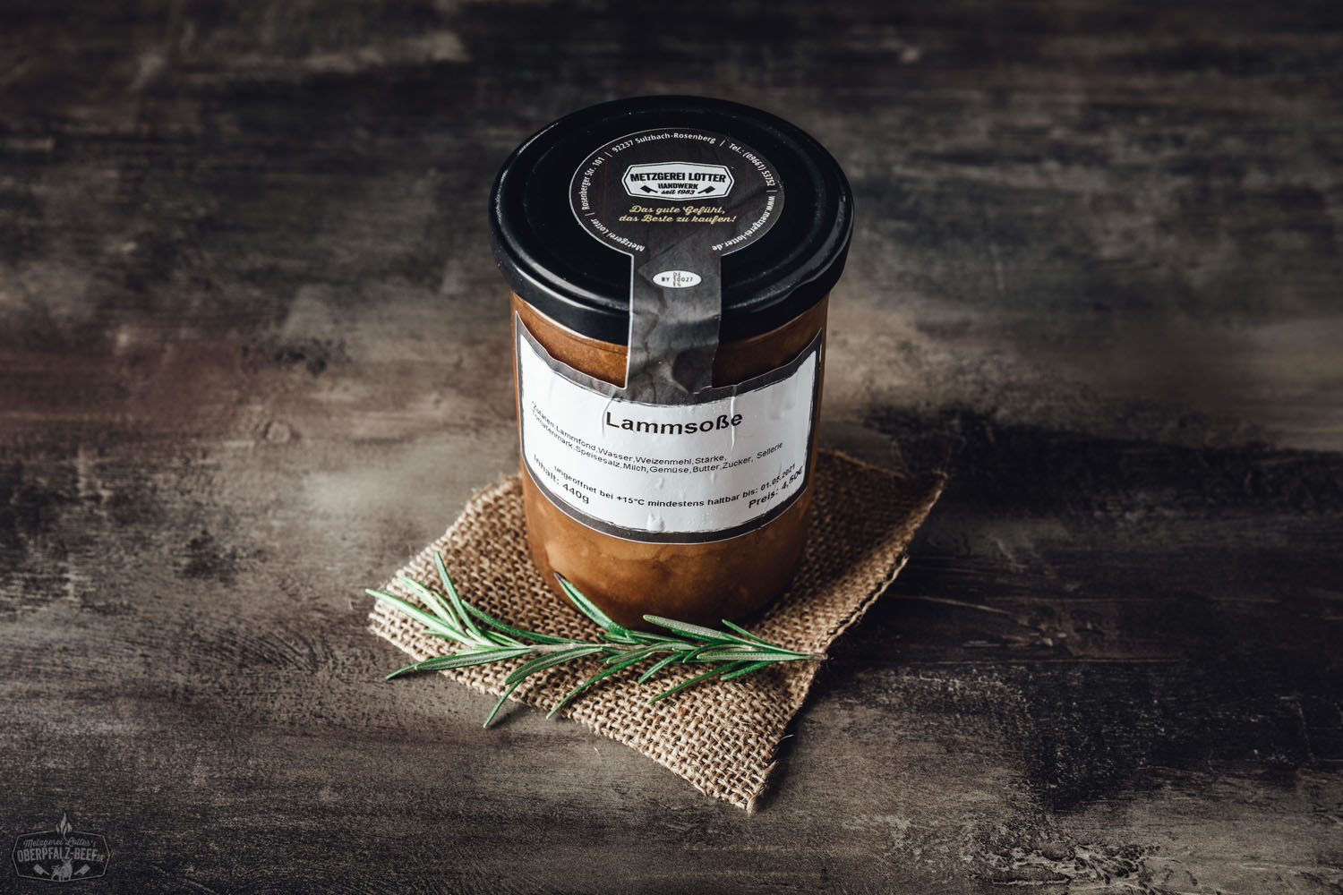 Lammsauce im Weckglas auf dunklem Untergrund, daneben frische Kräuter, schwarze Pfefferkörner und grobes Meersalz – hochwertige, hausgemachte Soße für Lammgerichte in ansprechender Food-Präsentation.