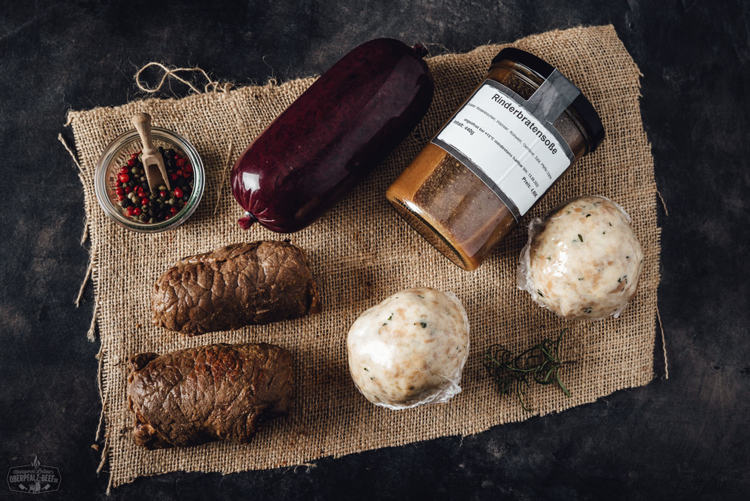 Oberpfälzer Rouladenbox mit regionalem Rindfleisch – Traditionell & frisch online bestellen Drei rohe Rinderrouladen, sorgfältig gewickelt und mit Küchengarn verschnürt, liegen nebeneinander in einer braunen Pappverpackung mit schwarzer Innenfolie; frisches, mageres Qualitätsfleisch aus der Oberpfalz, ideal für traditionelle Rouladengerichte.