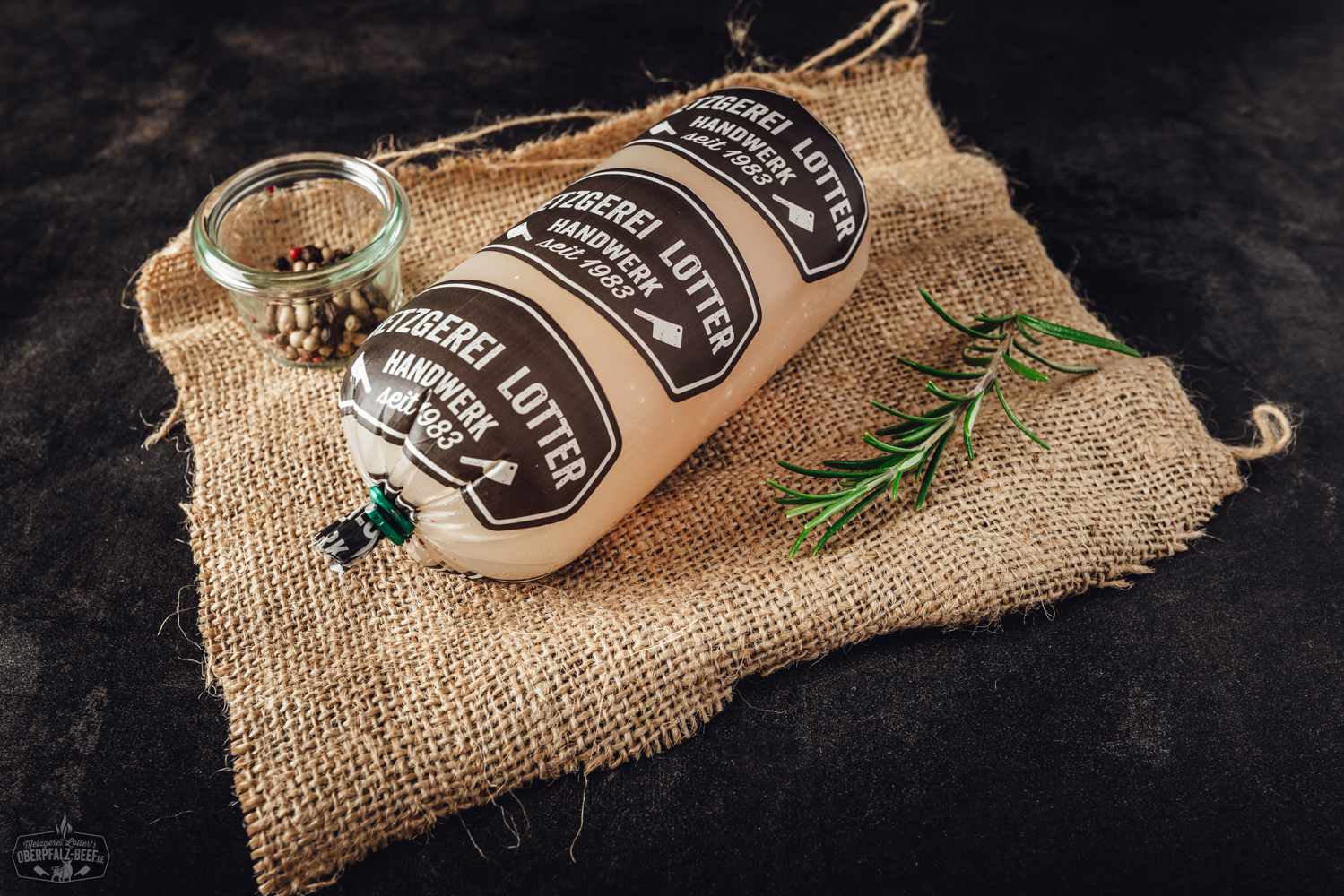 Geöffnete Konservendose mit grober Schinkenwurst auf weißem Hintergrund; die Wurst zeigt eine rosa-rote Farbe mit sichtbaren Speckstücken, Produktetikett mit Marke „Oberpfalz Beef“ und Beschriftung gut lesbar – hochwertige Fleischkonserve aus Bayern.