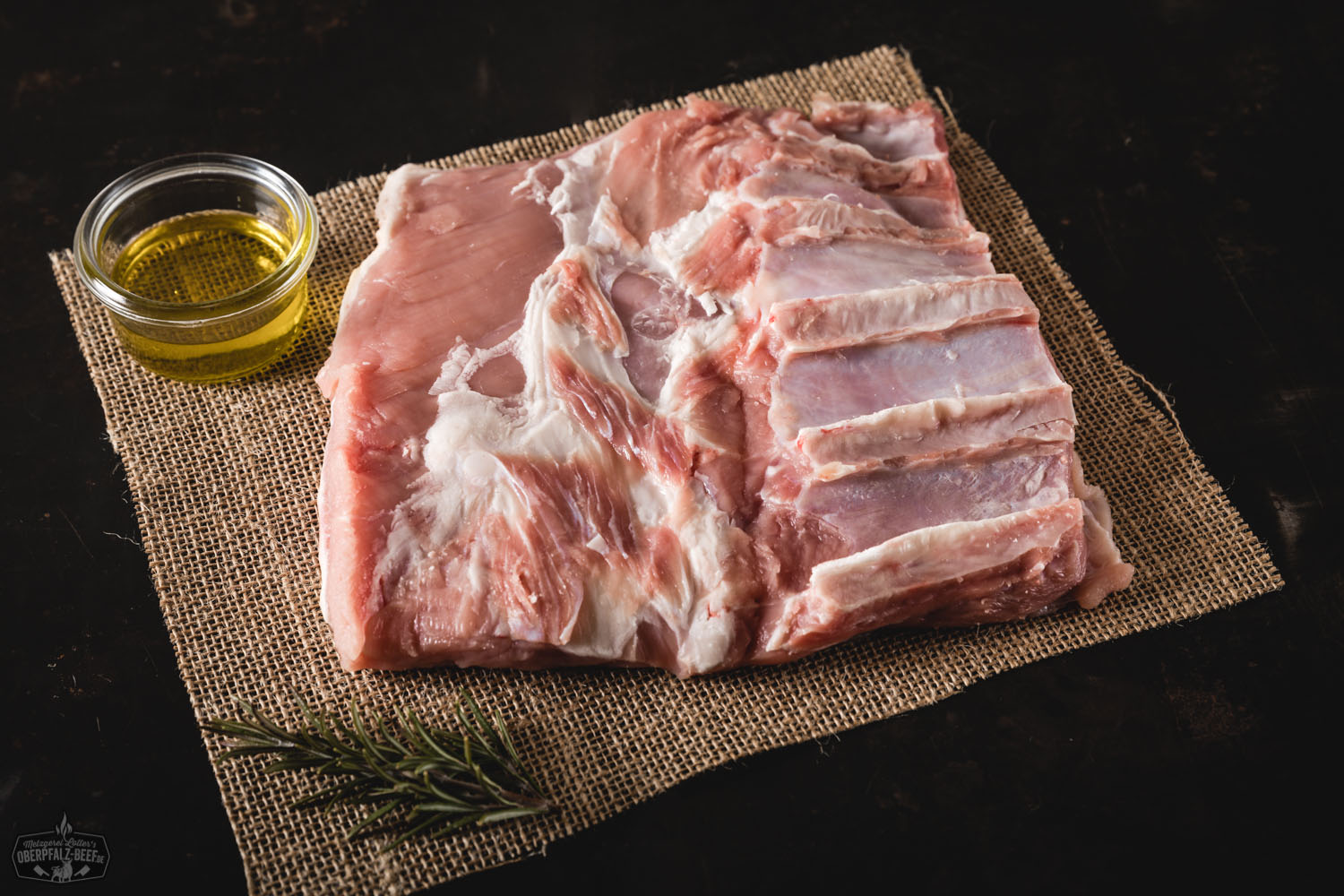 Kalbsbrust vom Oberpfälzer Milchkalb roh auf Holzbrett – hochwertiges Frischfleisch für feine Küche Rohe Kalbsbrust vom Oberpfälzer Milchkalb auf dunklem Untergrund, verziert mit frischen Kräutern, Knoblauch, schwarzem Pfeffer und grobem Salz – hochwertiges Fleischstück für Braten oder Grillgerichte, ideal für Feinschmecker und regionale Küche.