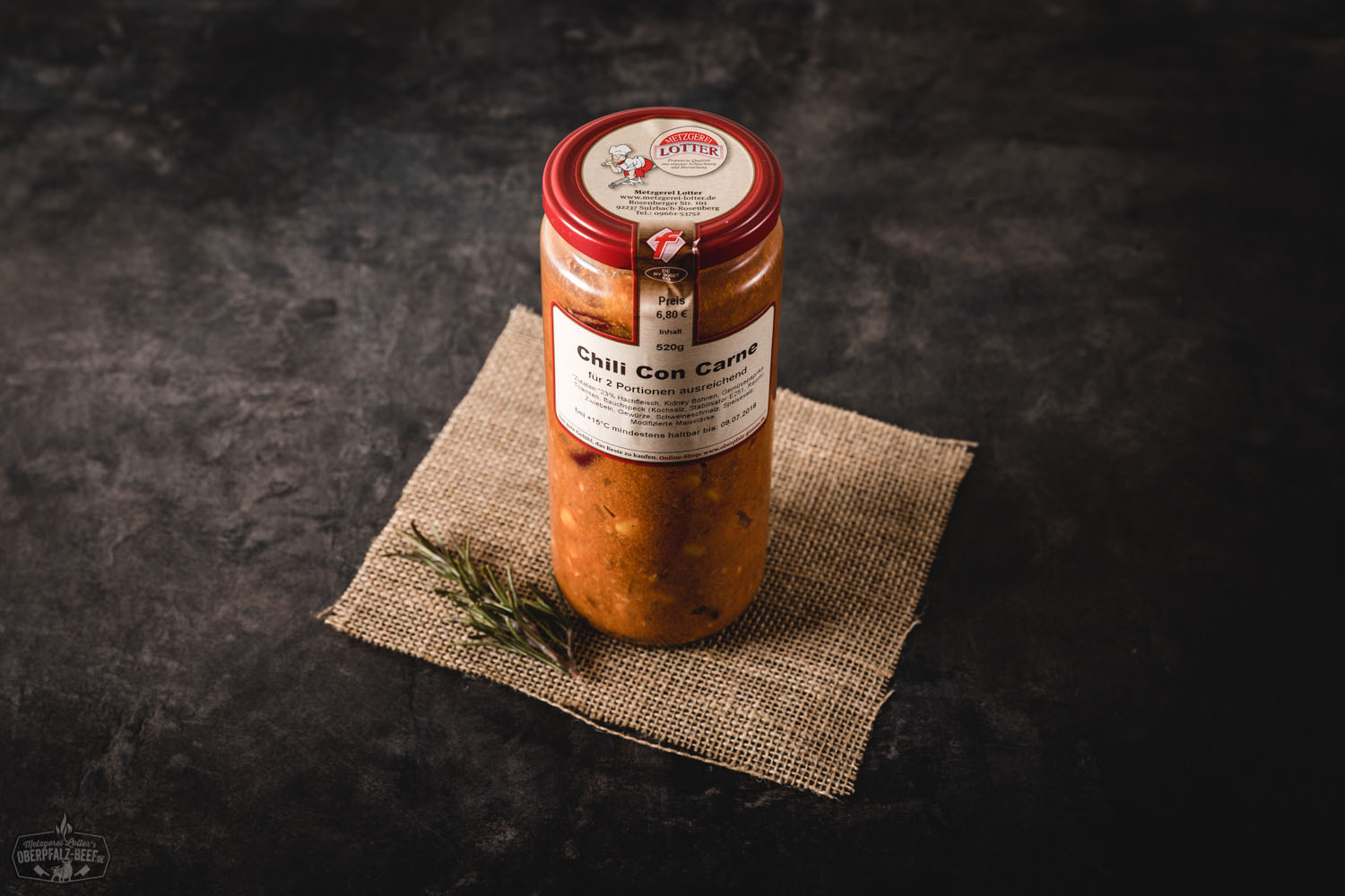 Chili con Carne im Einmachglas, rustikal angerichtet auf einem Holzbrett mit roten Chilischoten und Brotscheiben daneben – herzhafter Eintopf mit Hackfleisch, Bohnen und Mais, ideal für Vorratshaltung oder Geschenkidee im Glas.