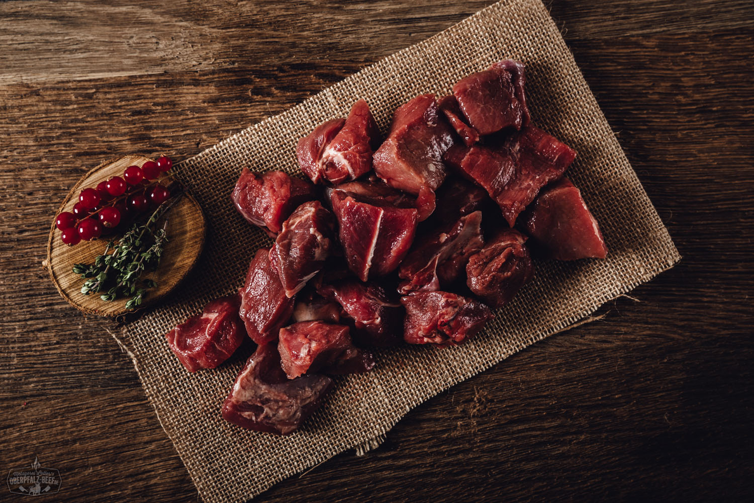 Rohes Edelgulasch vom Oberpfälzer Wildschwein in gleichmäßig geschnittenen, saftigen Würfeln auf einem rustikalen Holzbrett mit frischen Rosmarinzweigen und Pfefferkörnern, ideal zum Schmoren oder Braten – hochwertiges Wildfleisch aus regionaler Herkunft.