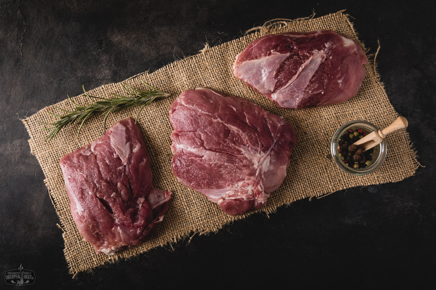 Cuscino vom Oberpfälzer Landschwein – zartes Schweinefleisch für Grill & Küche Nahaufnahme eines saftig gegrillten Cuscino-Steaks vom Oberpfälzer Landschwein auf einem dunklen Holzbrett, serviert mit Rosmarin, Meersalz und geröstetem Gemüse – traditionelles bayerisches Fleischgericht in hochwertiger Qualität.