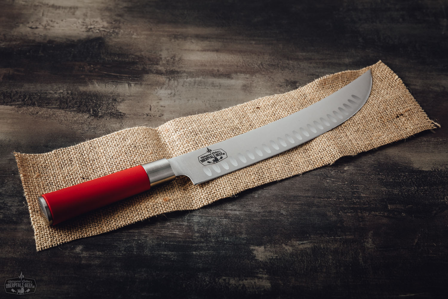 Grillmesser Dick Red Spirit mit rotem Griff – Profi Küchenmesser für Fleisch und BBQ Grillmesser mit rotem Griff aus der „Red Spirit“-Serie von Dick, Modell „Hecktor“, liegt auf dunklem Untergrund – hochwertiges, scharfes BBQ-Messer für Fleisch, ideal für Barbecue und Grillfans.