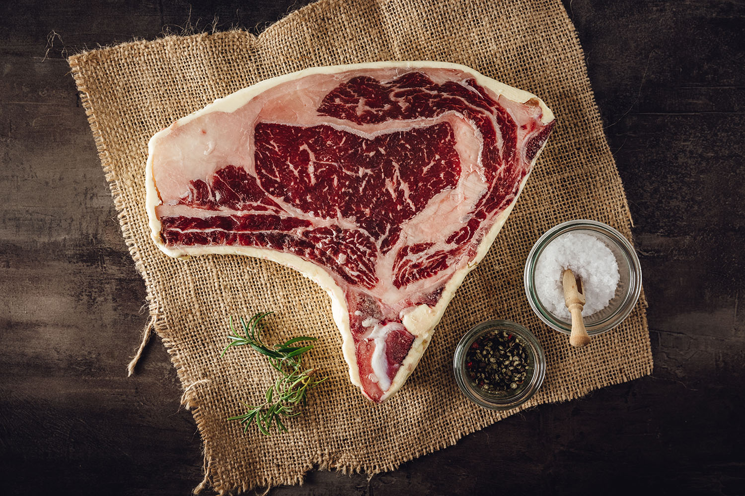 Entrecôte Ribeye Steak Bone-In Butter Aged vom Oberpfalz-Rind – Premium Dry Aged Beef Rohes Bone-in-Ribeye-Steak vom Oberpfälzer Rind auf dunklem Untergrund, marmoriert und dry aged, mit sichtbarem Fettauge – hochwertiges Entrecôte für Grill oder Pfanne.