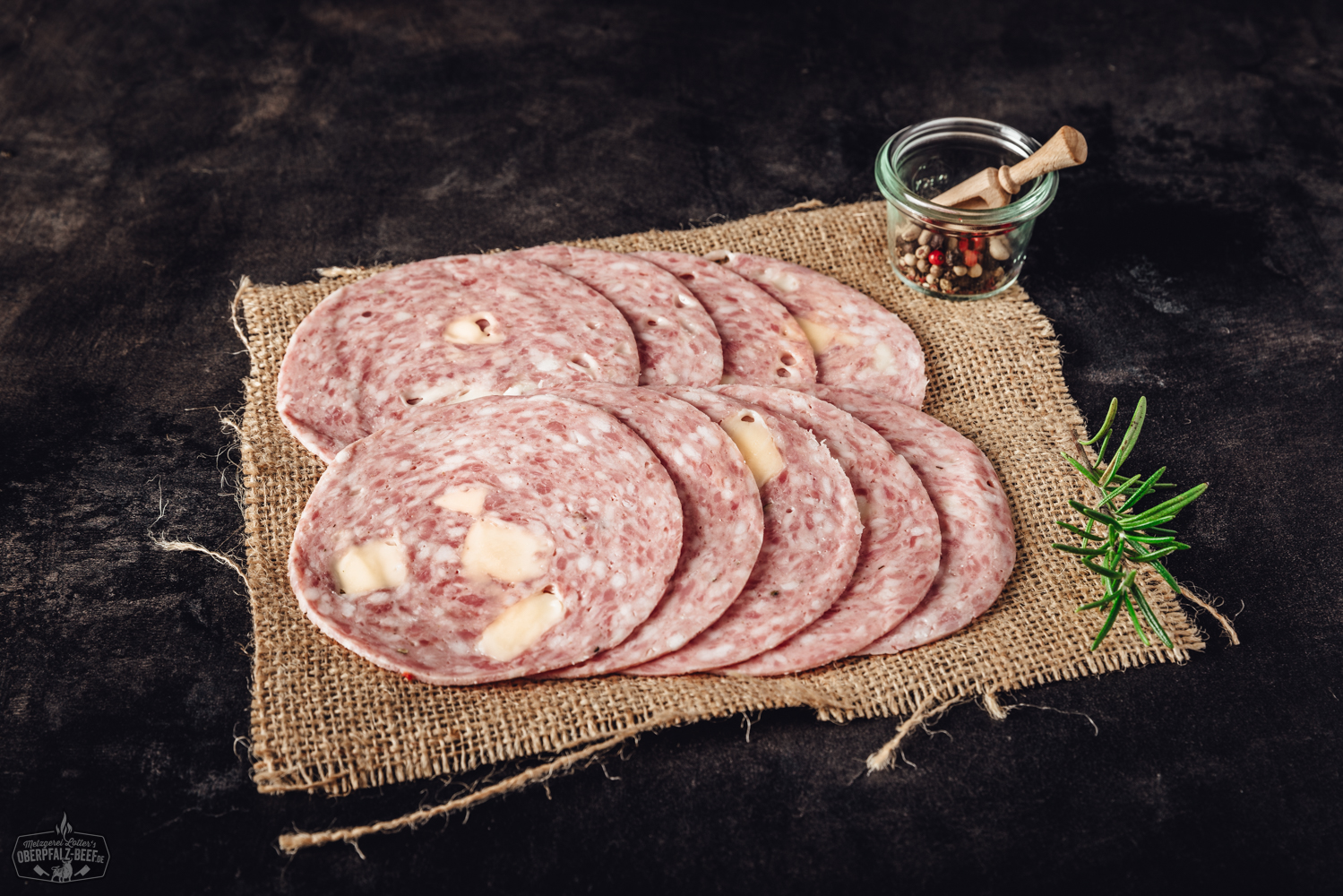 Geschnittene Käsebierwurst auf Holzbrett – herzhafte Wurst mit Käseanteil Käsebierwurst geschnitten - Delikatesse aus der Oberpfalz mit Bier- und Käsearomen, perfekt für Brotzeiten und Buffets. Frische, regionale Zutaten sorgen für einzigartigen Geschmack.