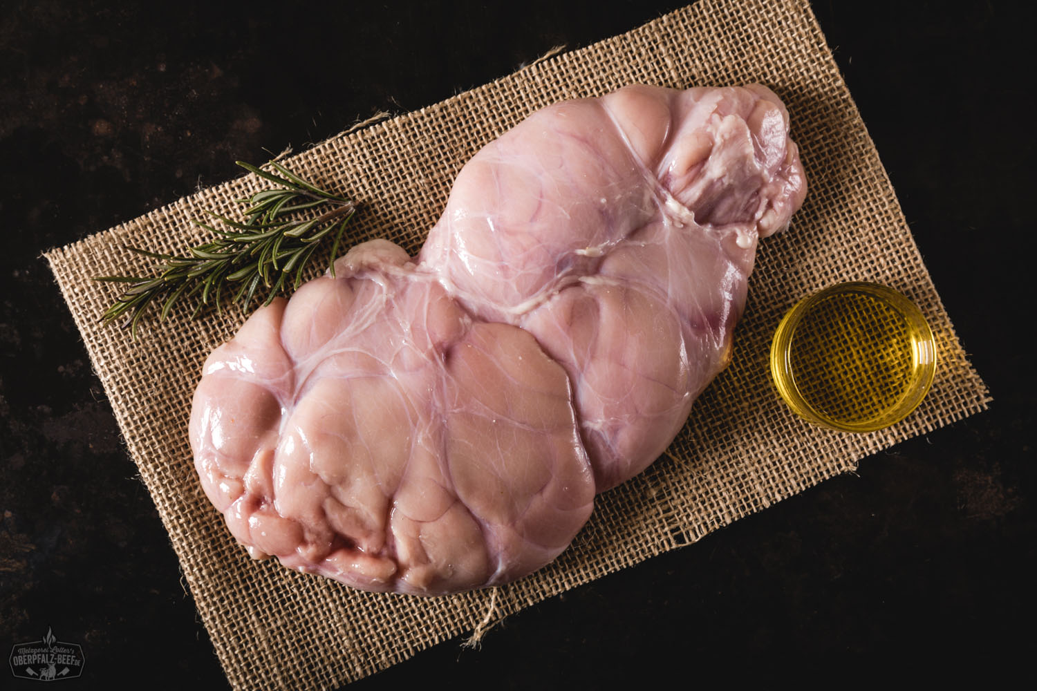 Rosa gebratenes Kalbsbries vom Oberpfälzer Milchkalb auf dunkler Servierplatte, angerichtet mit Wurzelgemüse, Kartoffelpüree, frischen Kräutern und Bratensauce – Gourmetgericht in Nahaufnahme.